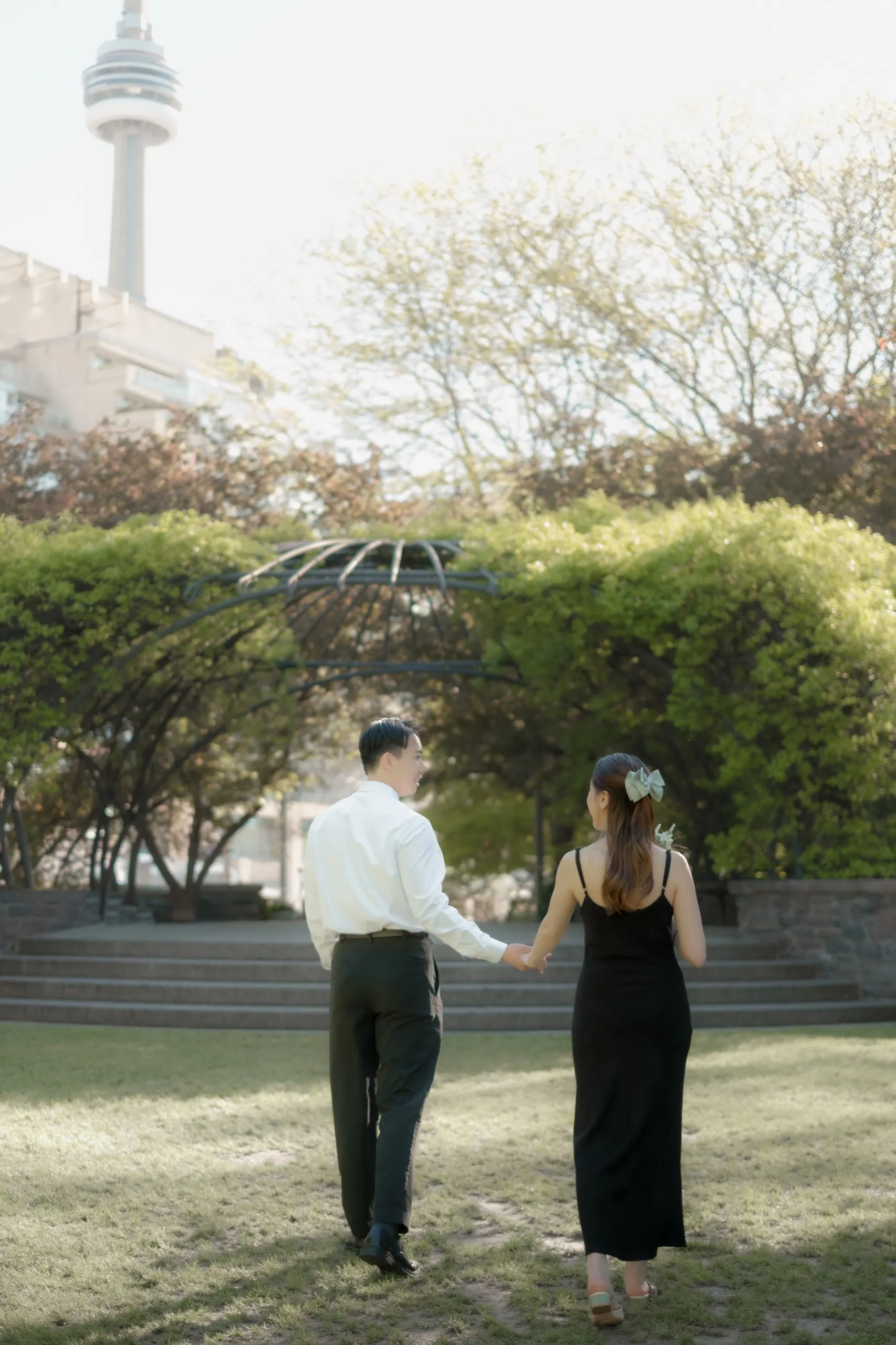 Josie and Nelson walk a garden path in soft afternoon haze with the CN Tower behind them at the Toronto Music Garden, by AD Photography