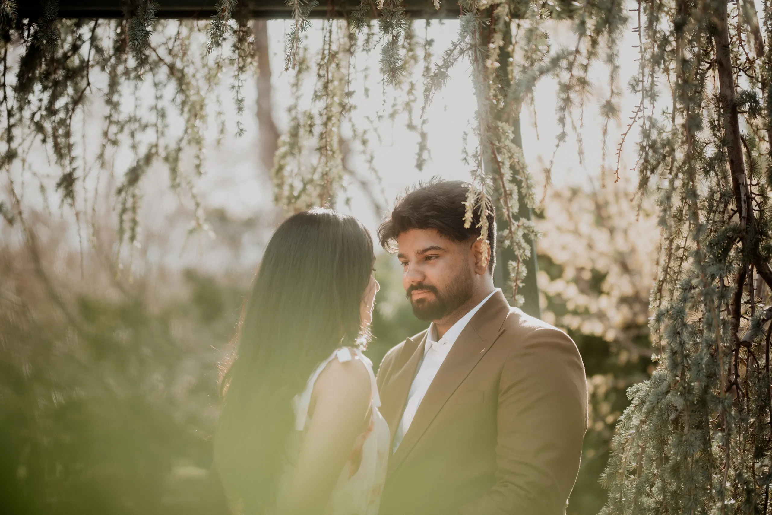 Mehak and Kamal framed by hanging cedar branches in an Okanagan Japanese garden, by AD Photography