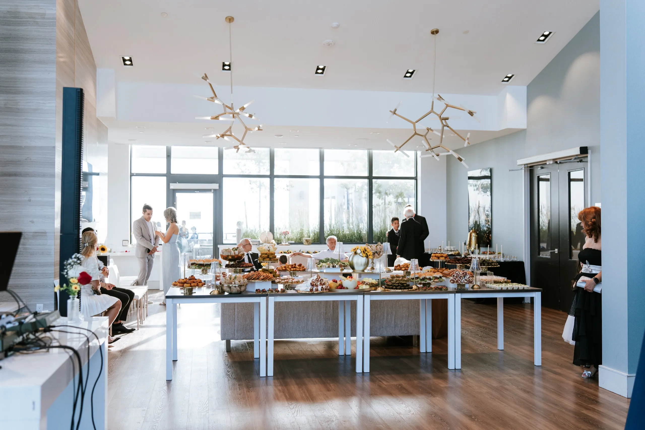 Guests gather around the long grazing tables as the glass walled party room in Maple opens for the anniversary celebration, by AD Photography