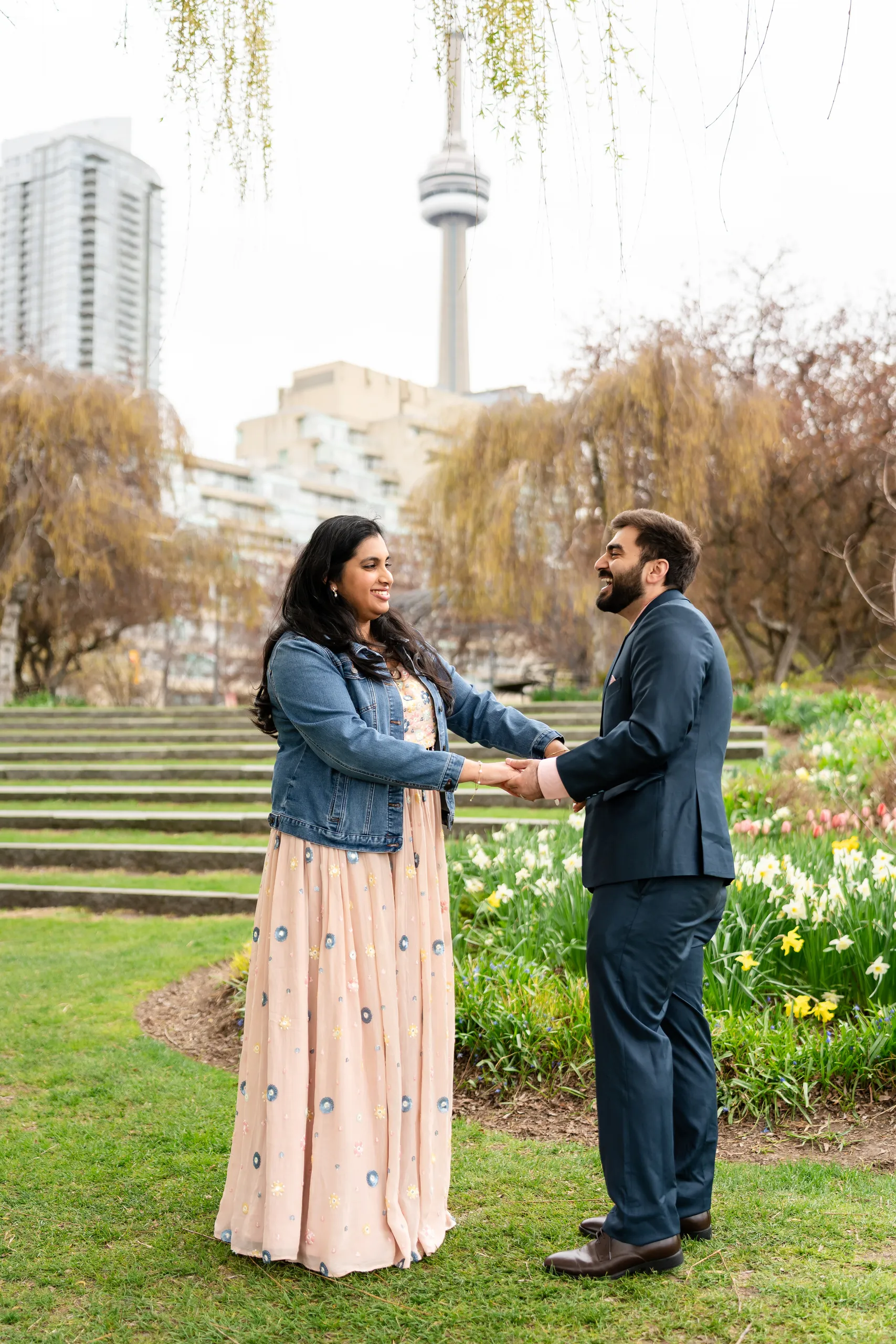 Abdullah and Nadia hold hands on the Toronto Music Garden lawn with the CN Tower behind them at their civil ceremony, by AD Photography