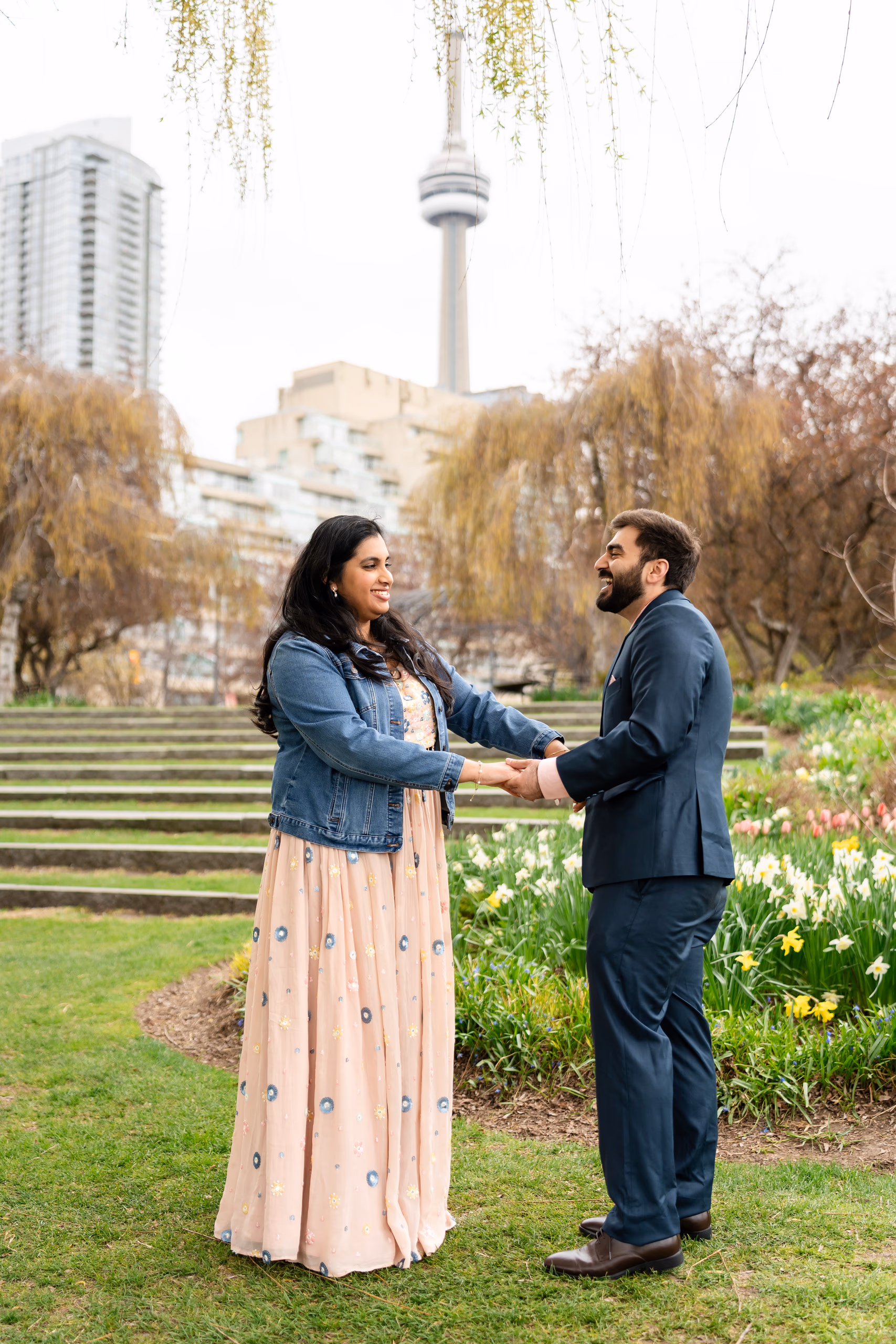 Abdullah and Nadia hold hands on the Toronto Music Garden lawn with the CN Tower behind them after eloping in Toronto, by AD Photography