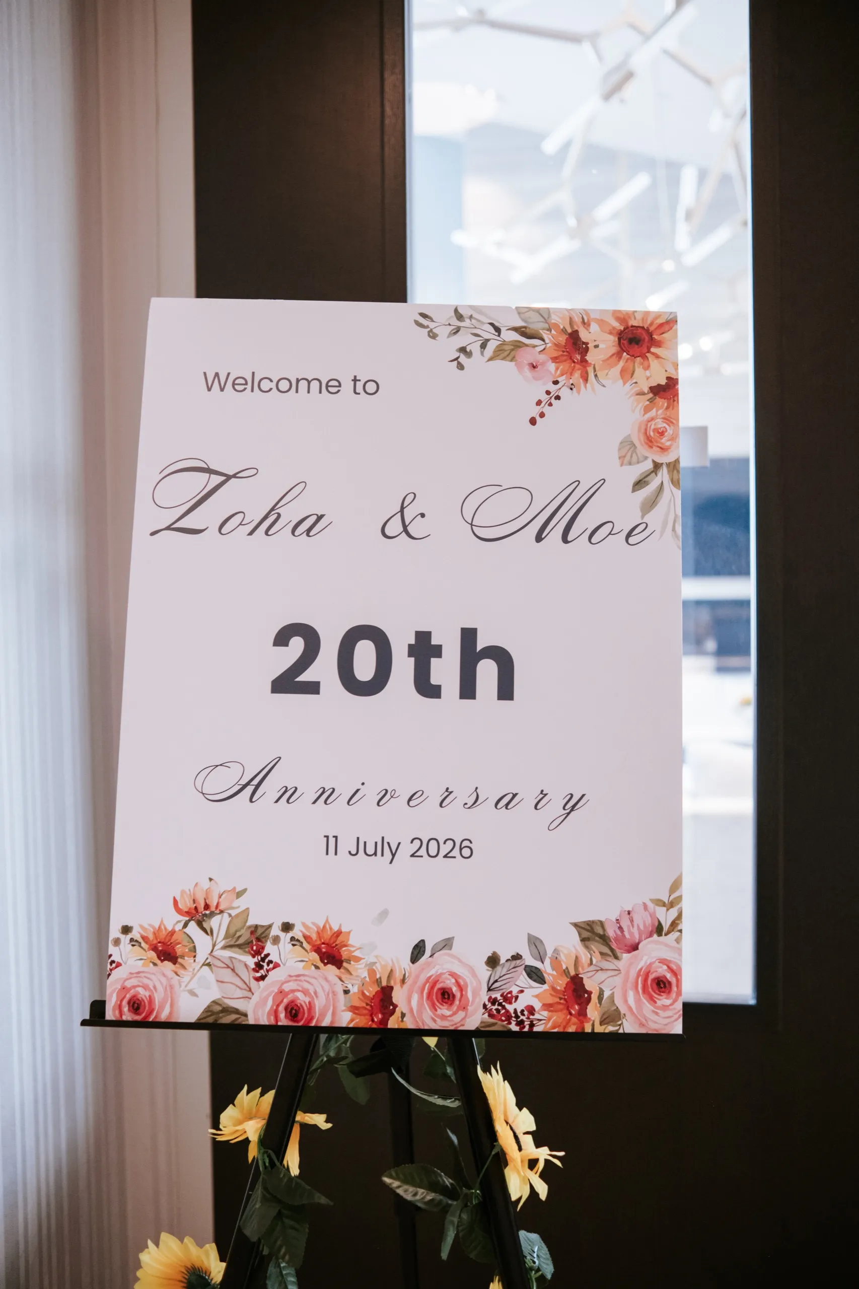 Welcome sign for Zoha and Moe's 20th anniversary framed by sunflowers at the entrance, by AD Photography