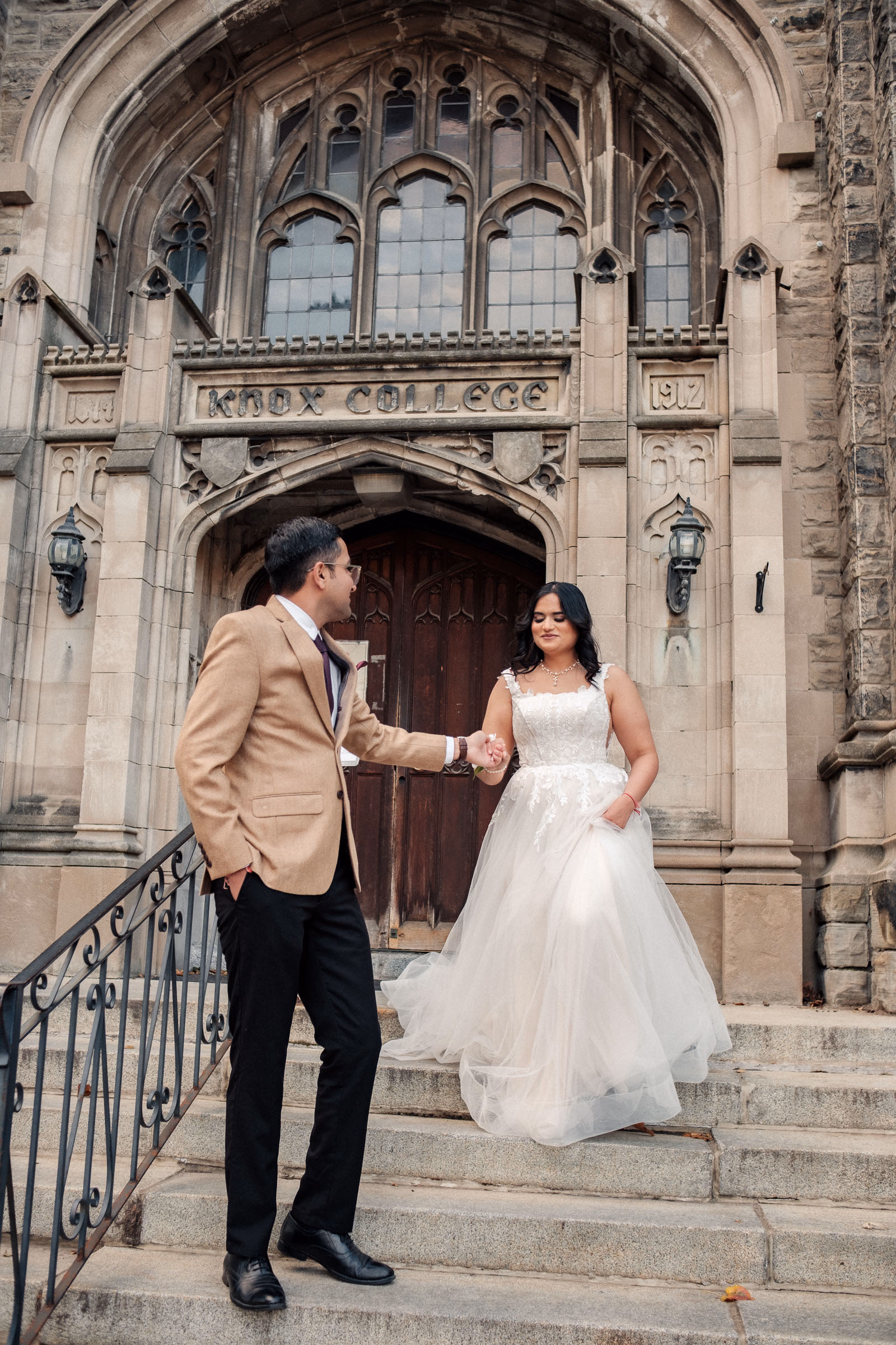A couple under the Gothic stone arches of Knox College at the University of Toronto in autumn light, by AD Photography