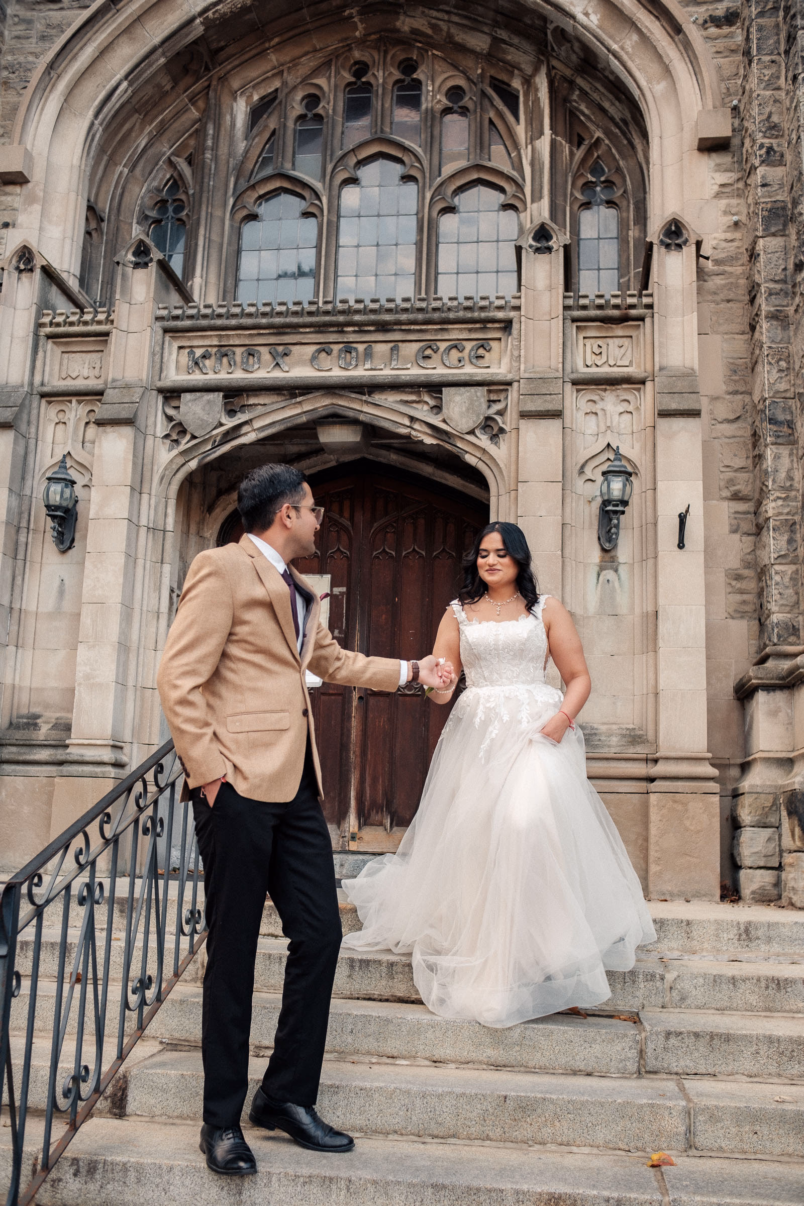 A couple under the Gothic stone arches of Knox College at the University of Toronto in autumn light, by AD Photography