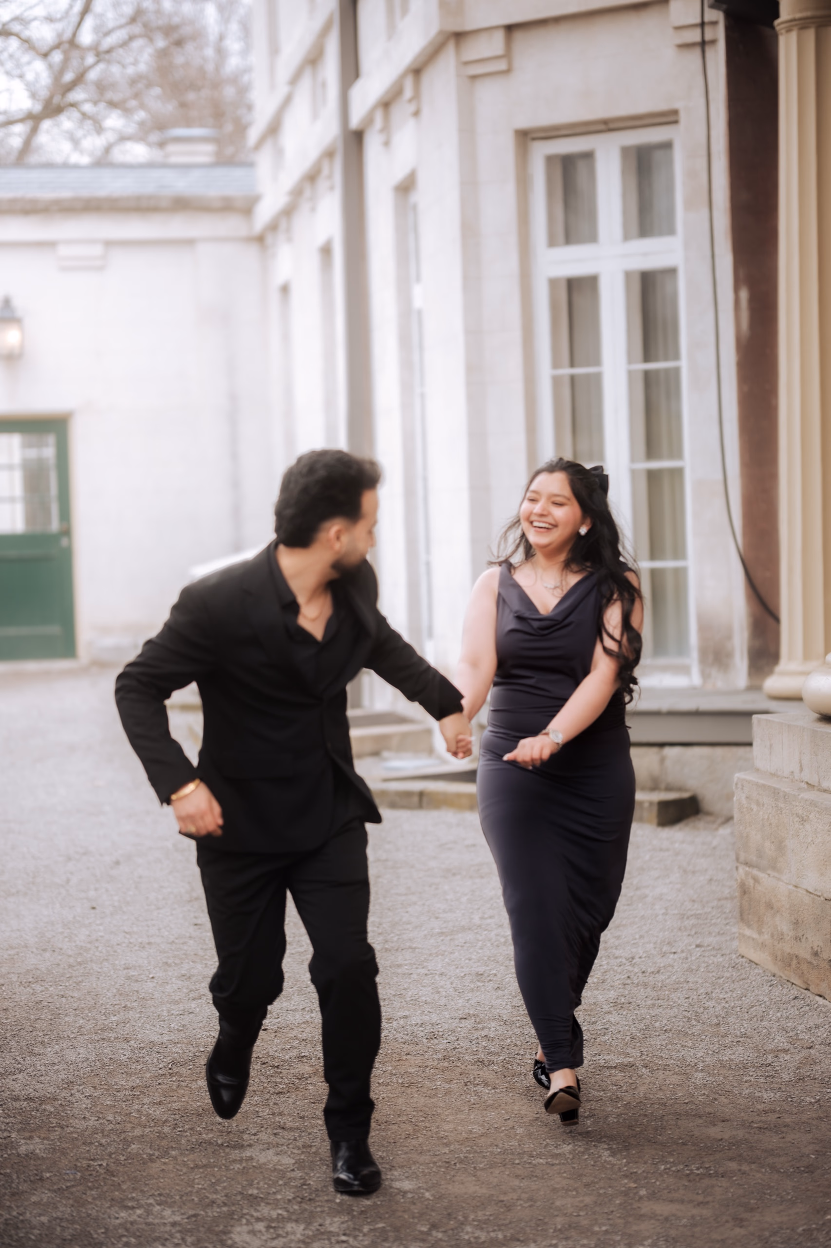A couple in front of the Italianate columned facade of Dundurn Castle in Hamilton, parkland and bare-limbed trees around them, by AD Photography