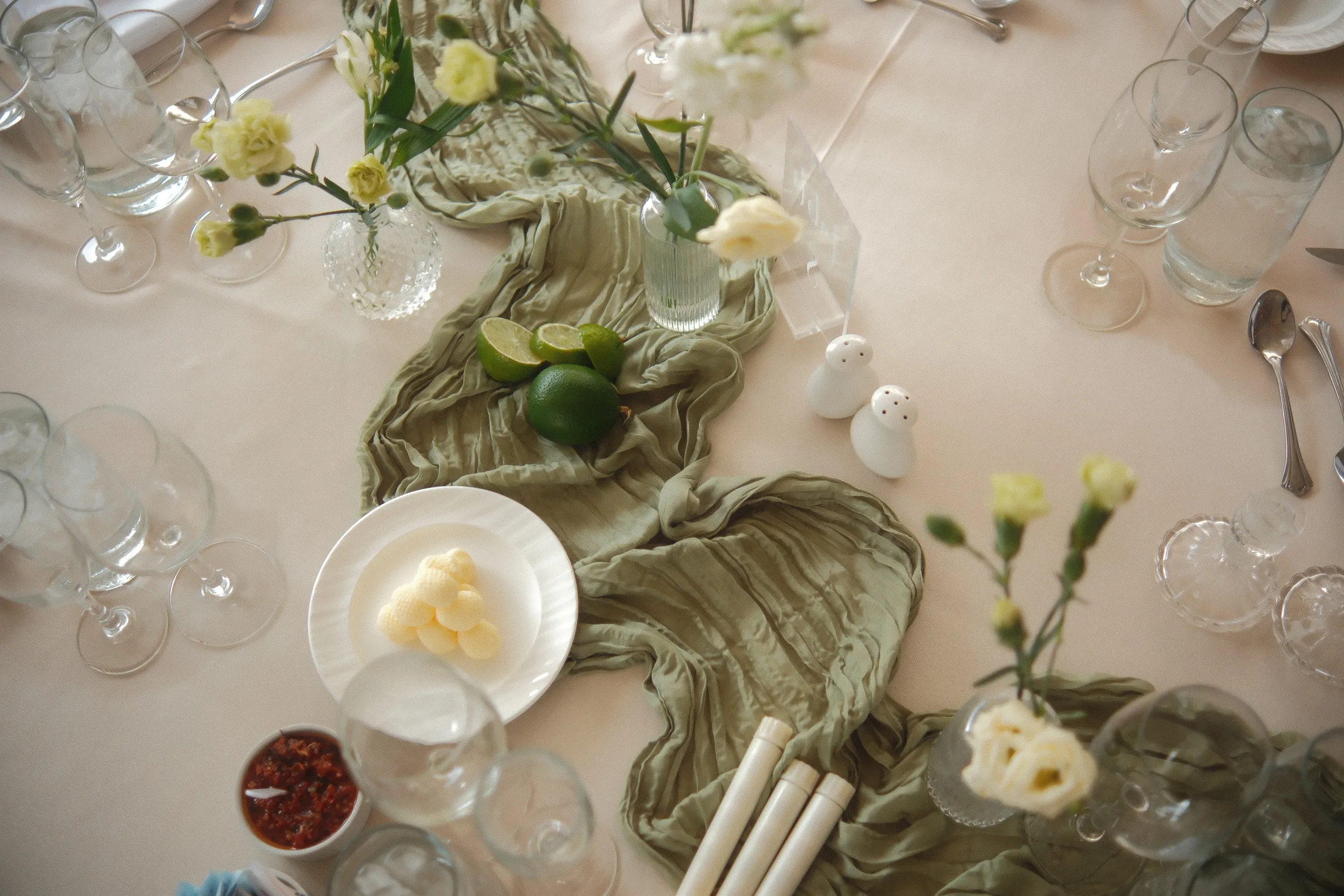 Reception table detail with sage runner, white blooms, fresh limes and polished glassware, by AD Photography