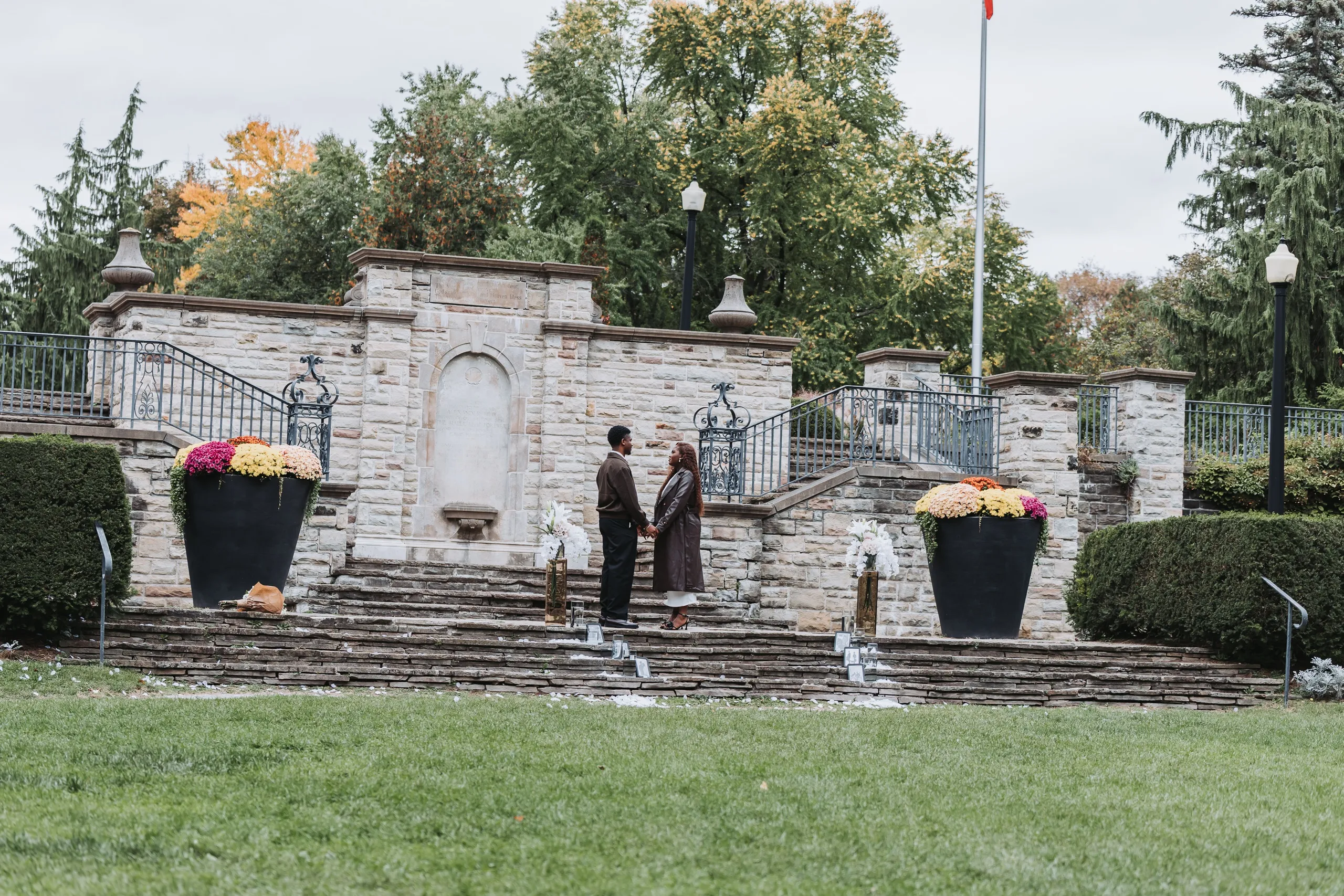 The stone terrace at Alexander Muir Memorial Gardens set with white lilies, framed photos and petals for the proposal, by AD Photography