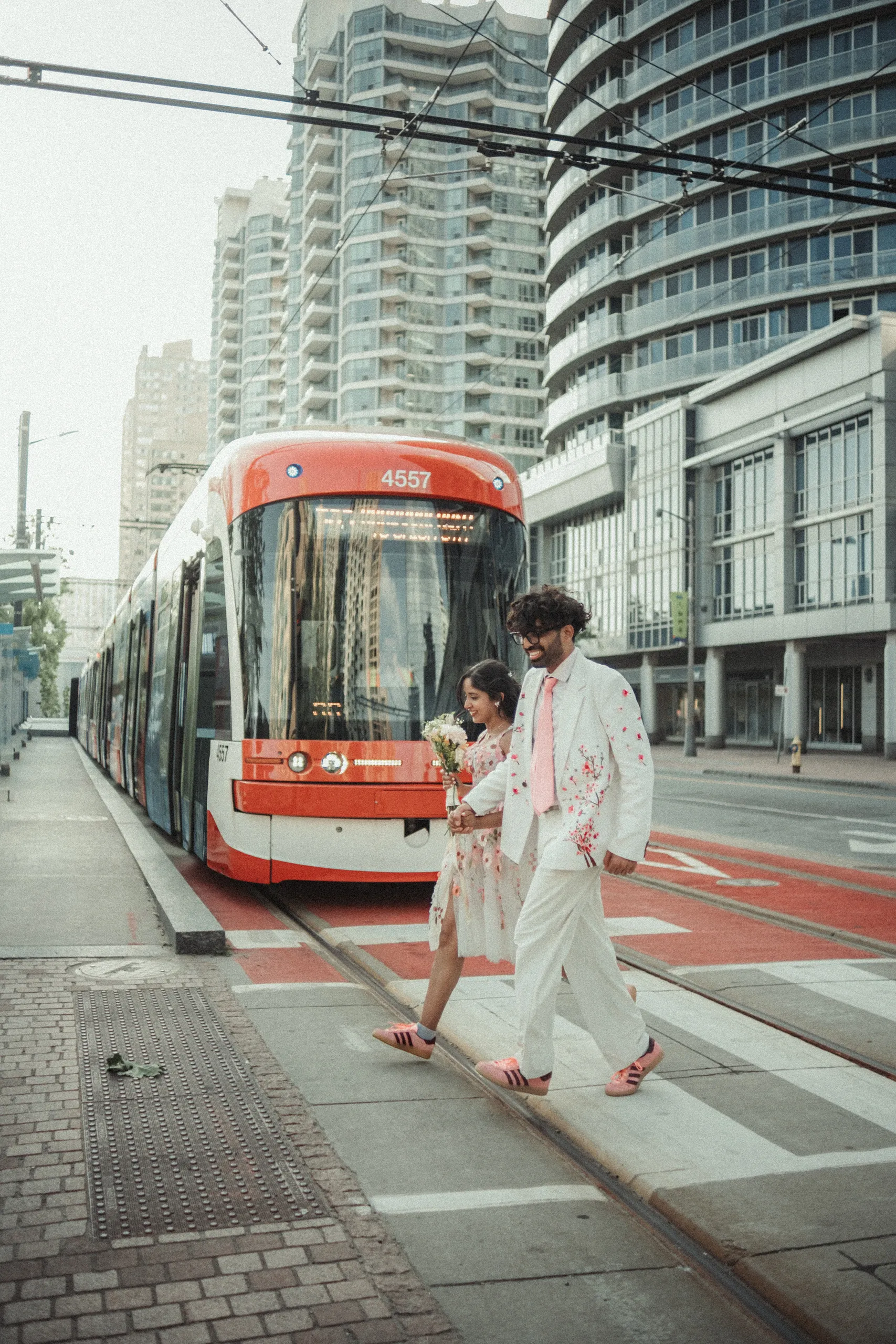 A Toronto streetcar passing behind Harsh and Payal on their wedding day downtown, by AD Photography