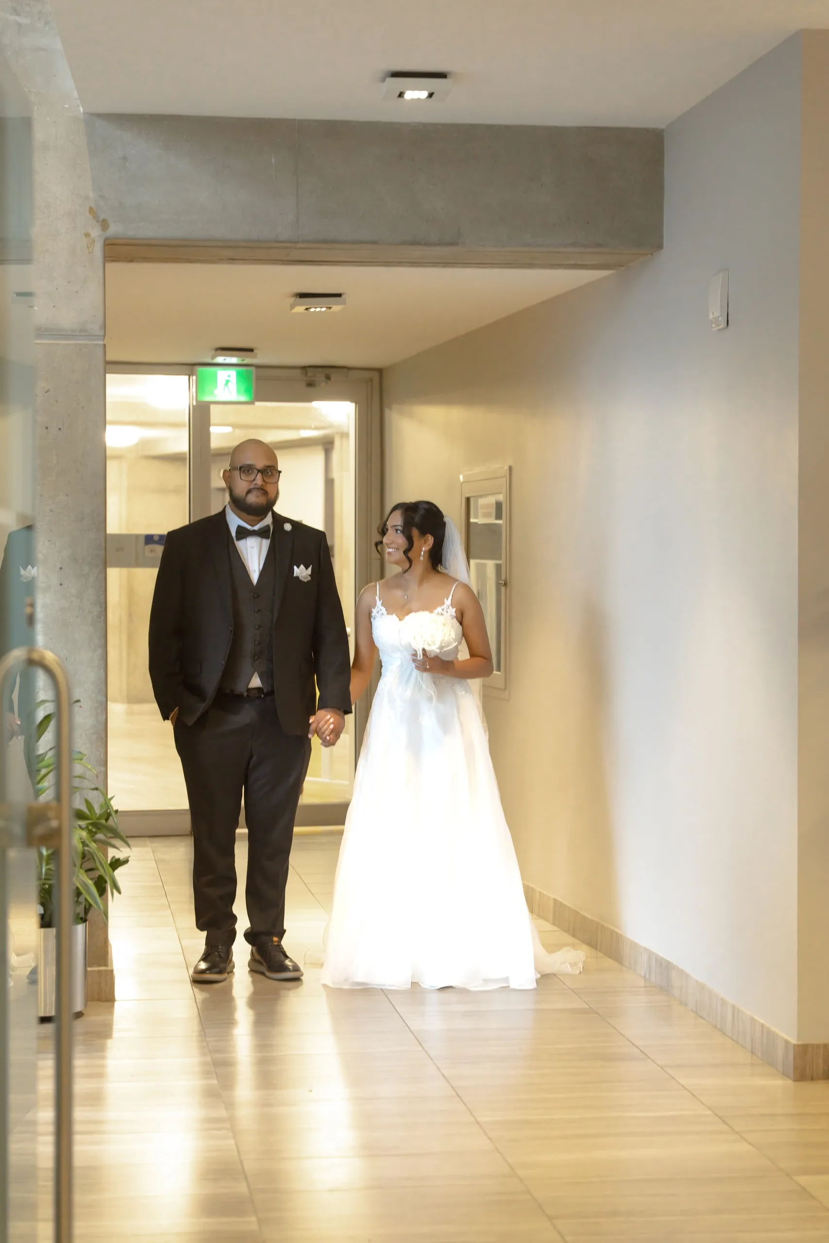 Bride and groom walk the corridor to their Toronto City Hall civil ceremony, by AD Photography