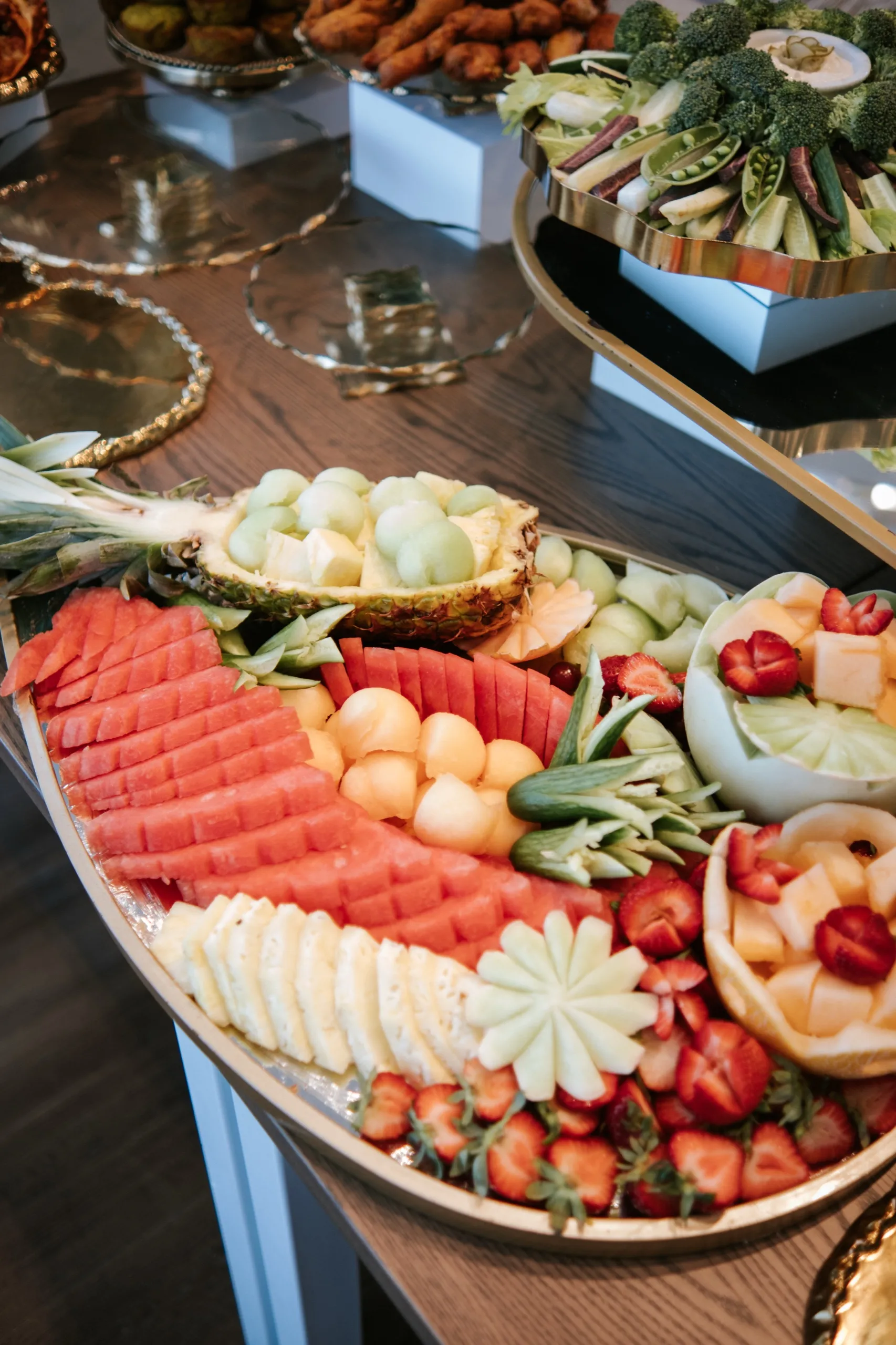 Carved pineapple boat and fresh fruit platter laid out for the anniversary celebration in Maple, by AD Photography