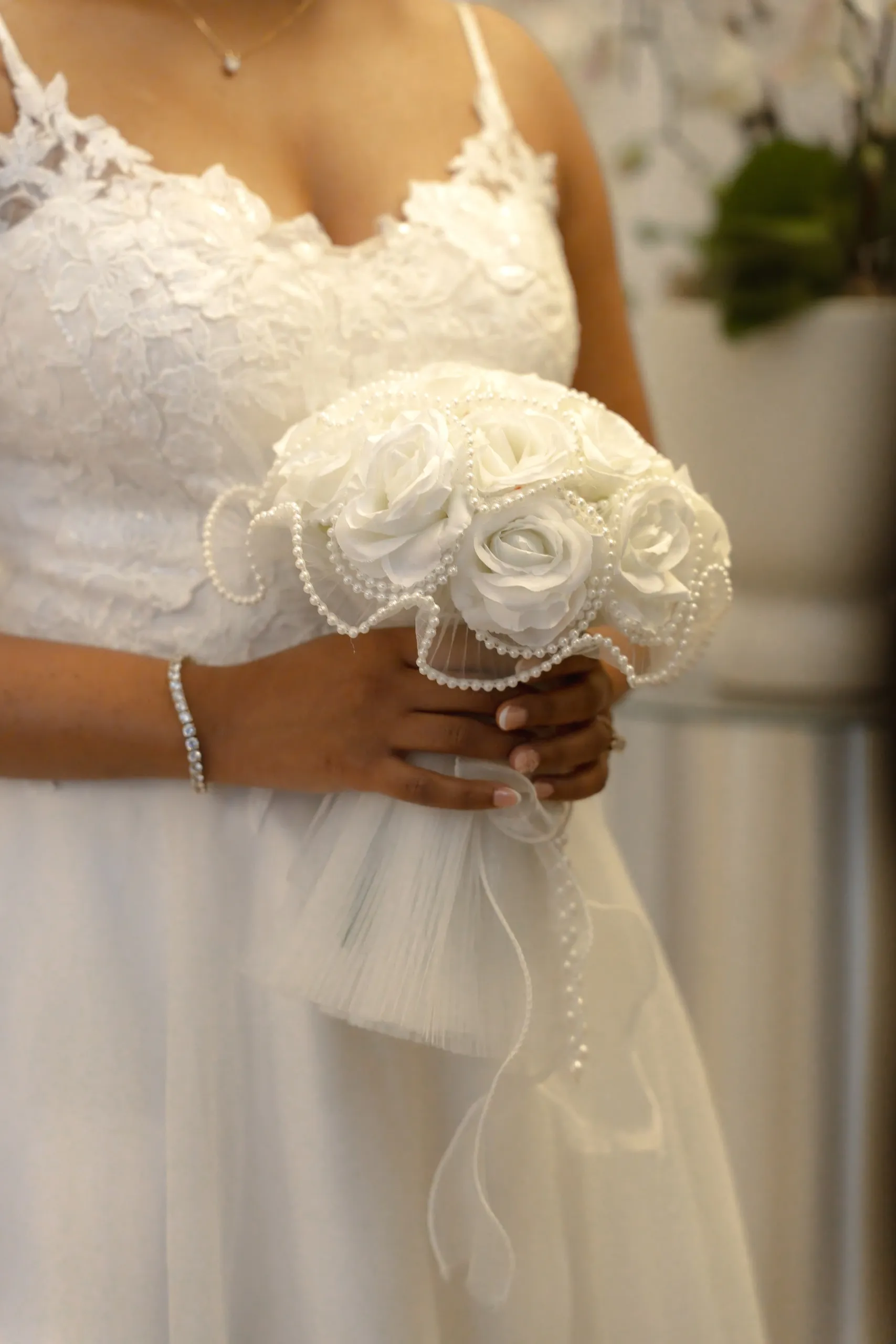 White rose bouquet with pearl strands against the bride's lace gown, by AD Photography