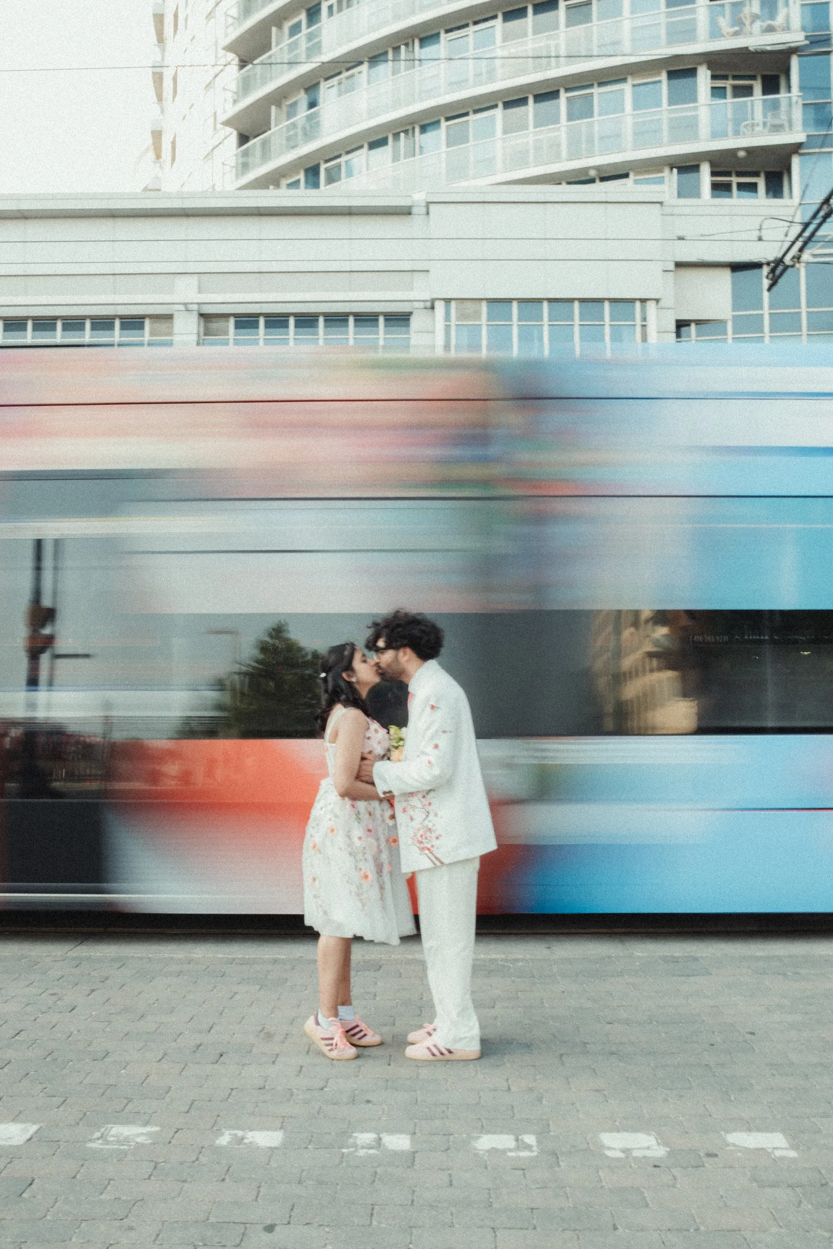 Harsh and Payal kissing perfectly still as a Toronto streetcar blurs past behind them, by AD Photography