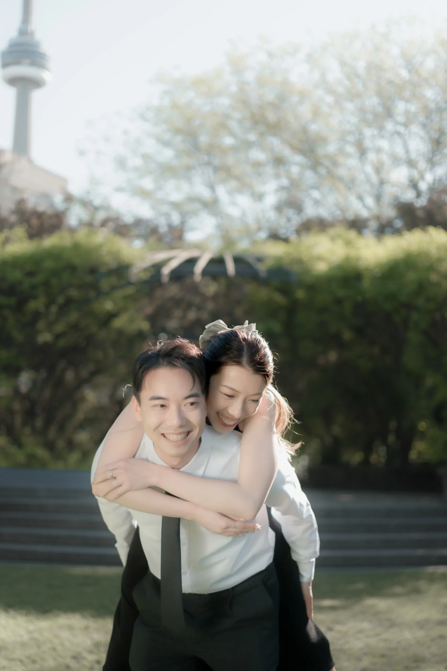 Nelson carries Josie piggyback along the Harbourfront with the CN Tower rising behind them, by AD Photography