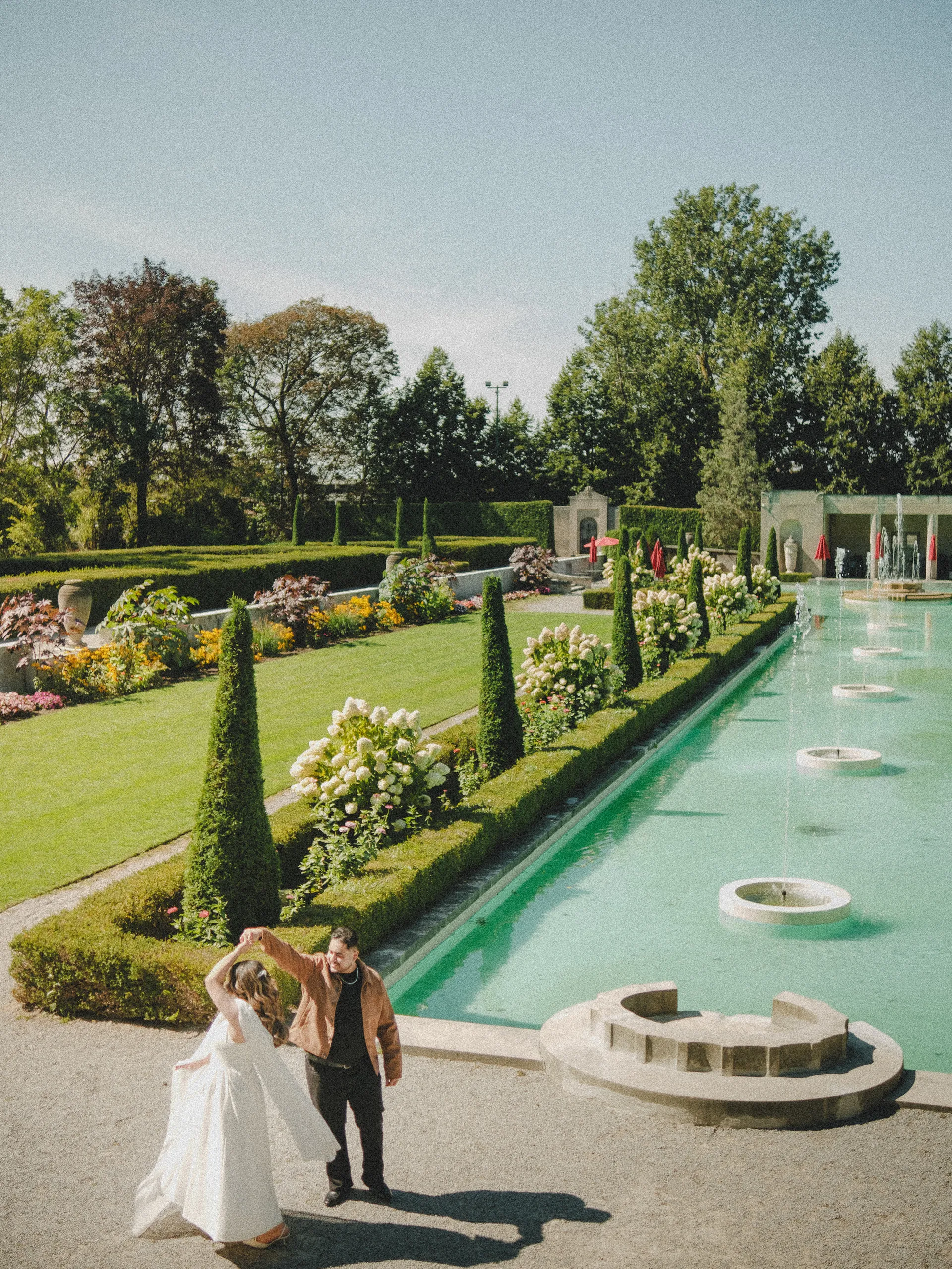 Looking down the long pool in Parkwood Estate's Formal Garden as Maninder twirls Parneet, by AD Photography