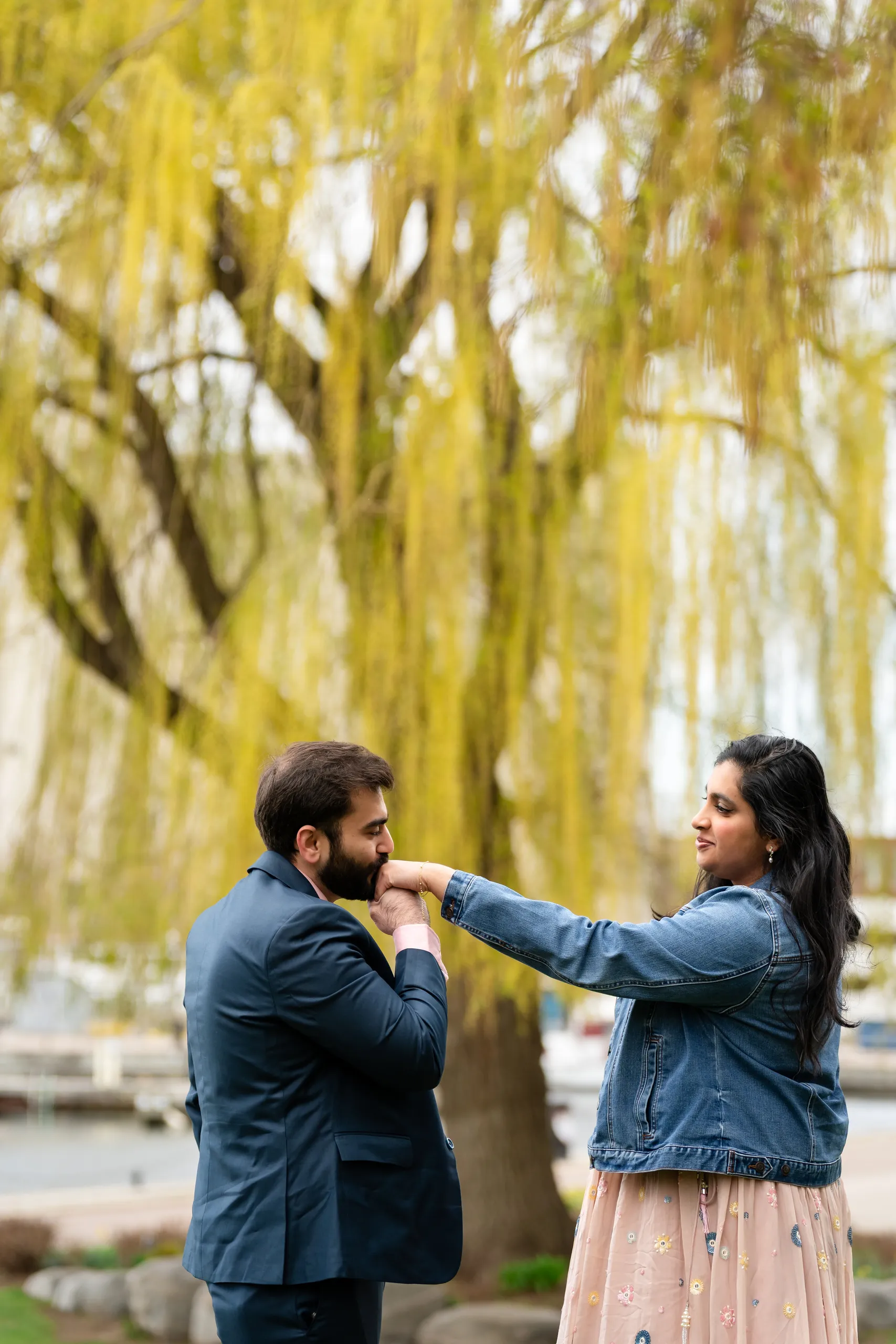 Abdullah kisses Nadia's hand in front of the golden willow at Toronto Music Garden, by AD Photography