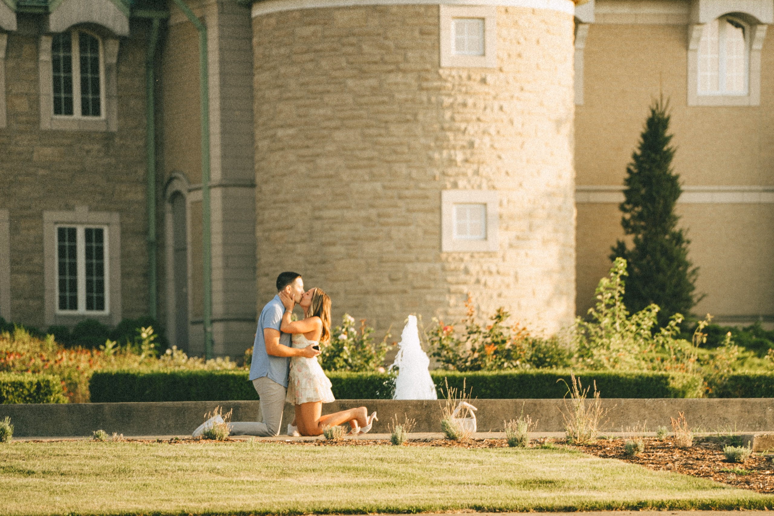 Donald kissing Ashley as she kneels into him beside the fountain at Château des Charmes winery seconds after she said yes, by AD Photography