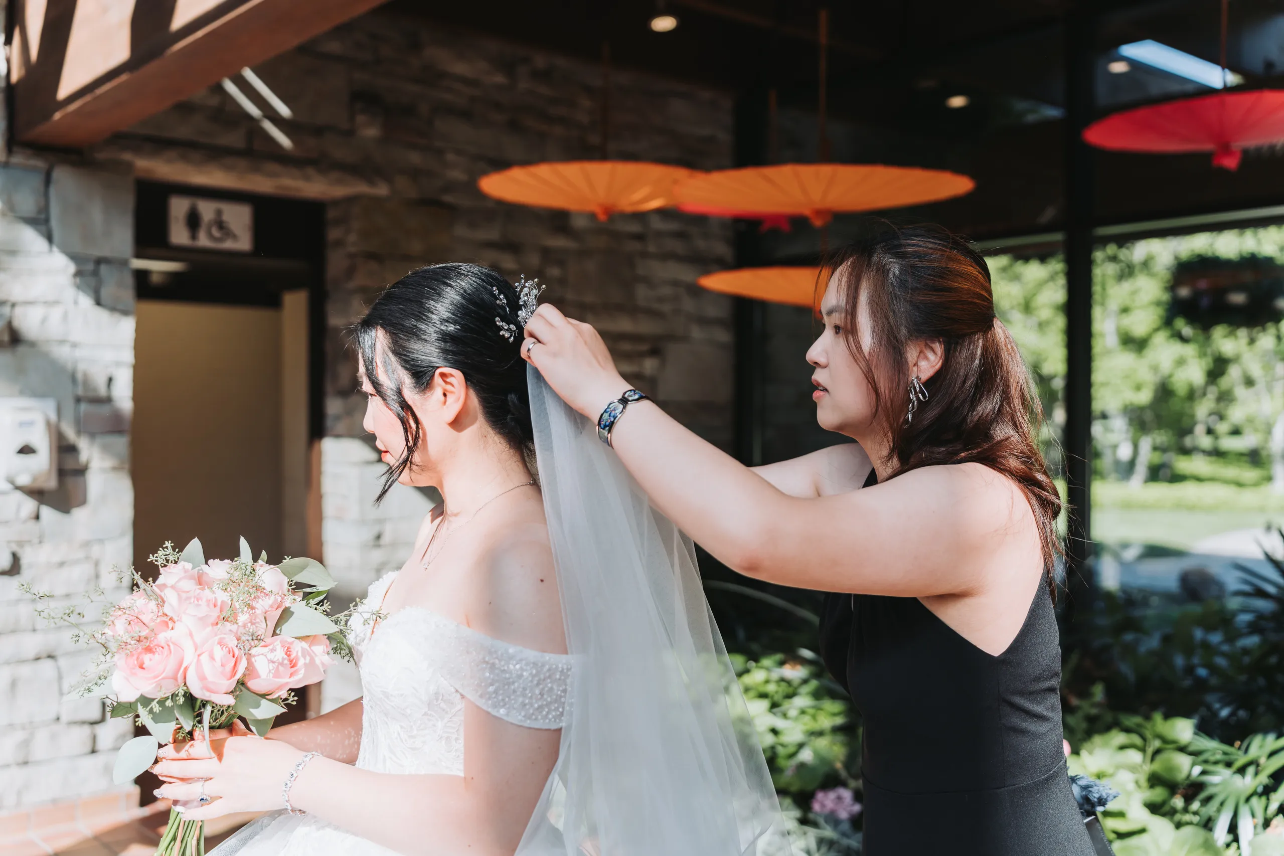 A bridesmaid pinning Karen's veil in the entrance breezeway at the Niagara Parks Botanical Gardens, by AD Photography
