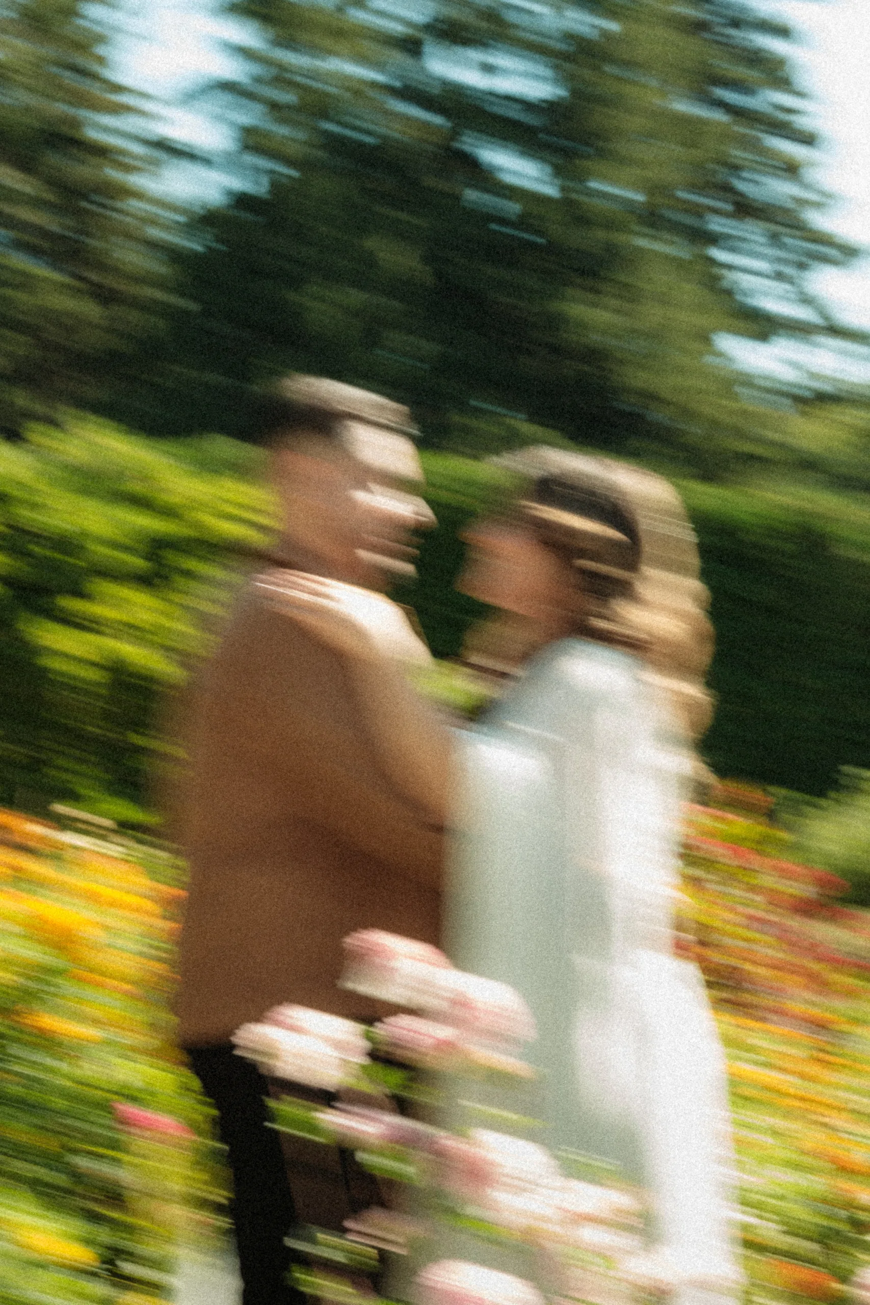Motion blur paints Maninder and Parneet face to face among the roses and orange blooms, by AD Photography
