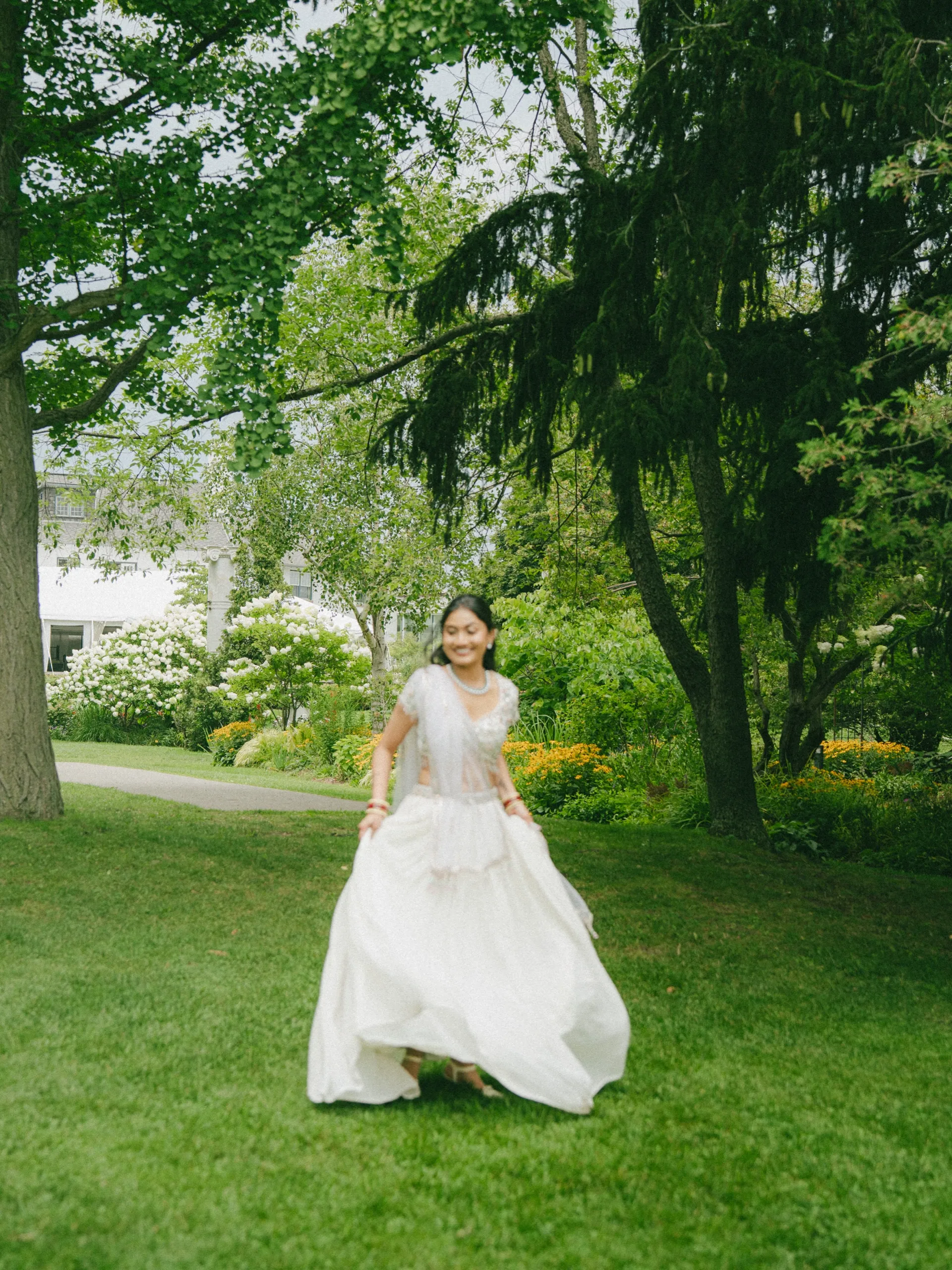 Soft motion blur of Nidhi twirling her lehenga skirt across the lawn at Guild Park and Gardens., by AD Photography