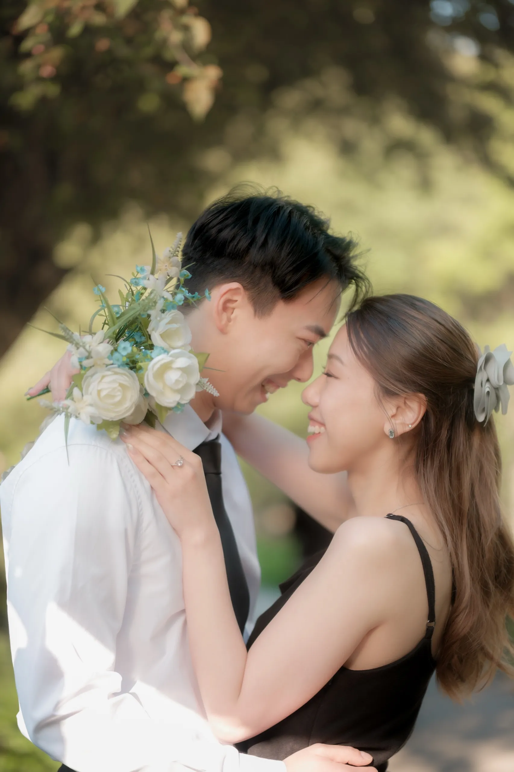 Josie and Nelson laugh forehead to forehead in a close garden embrace, by AD Photography