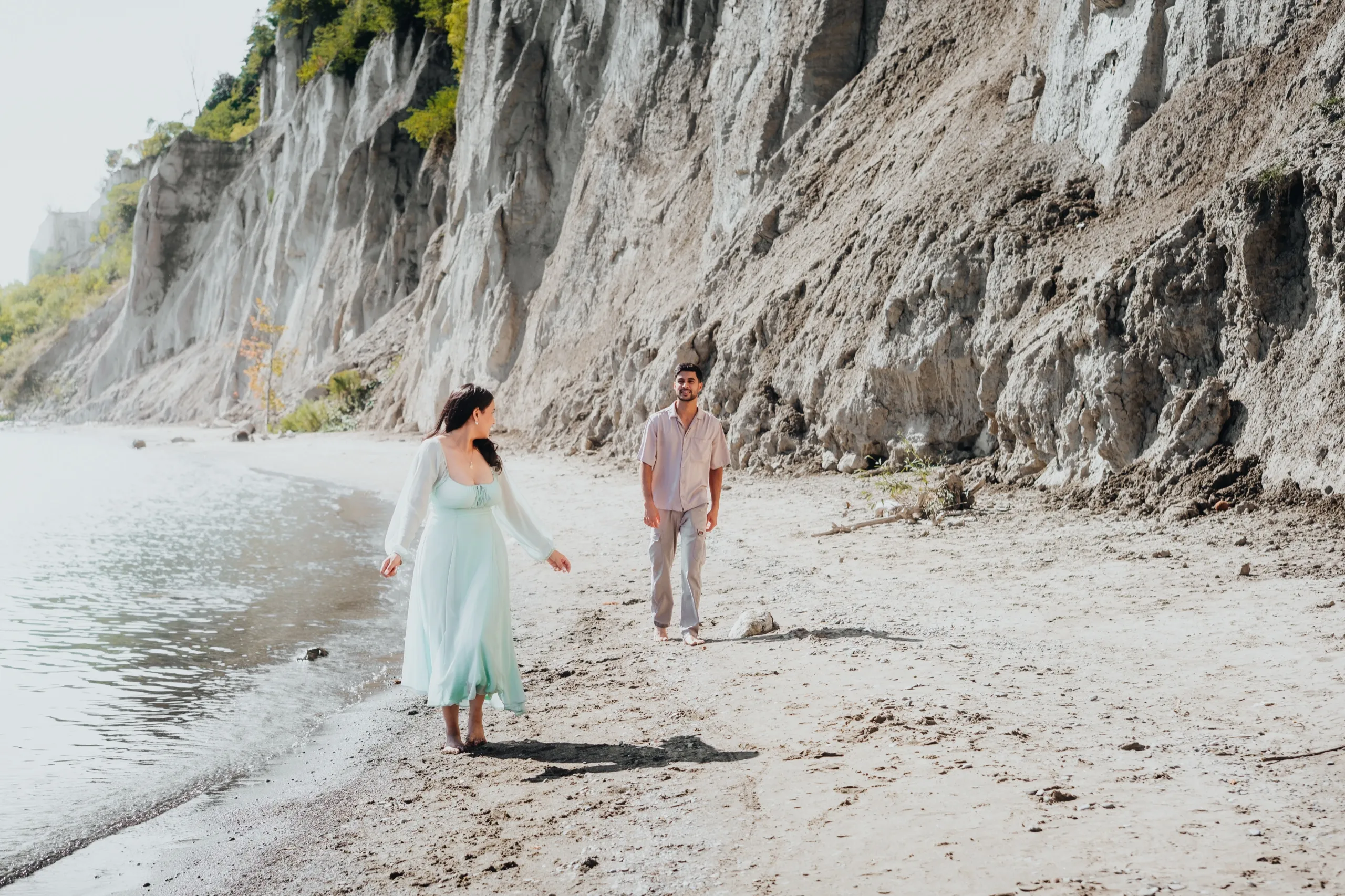 Swati looks back smiling as she leads Saksham along the Bluffs Beach sand, by AD Photography