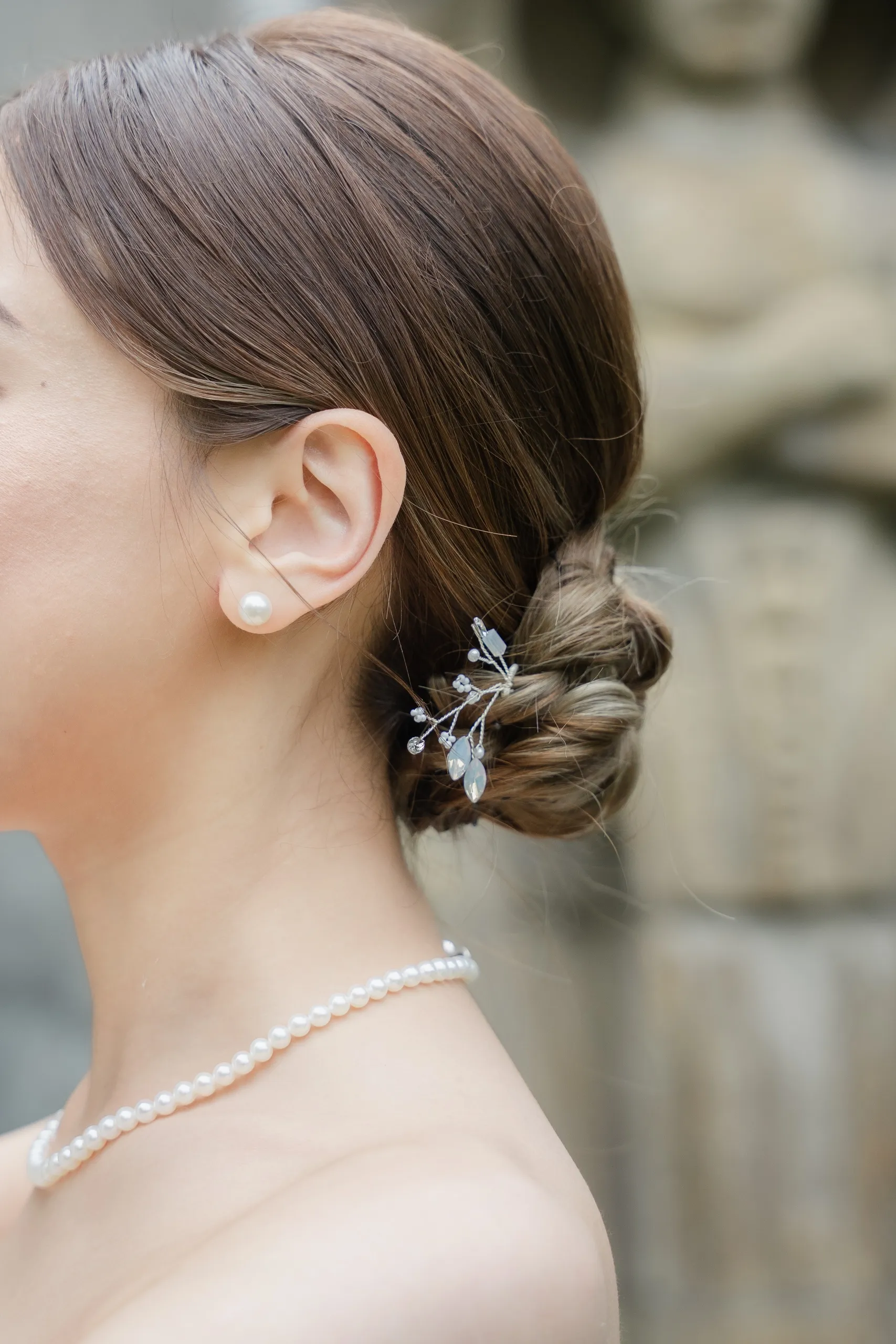 Close detail of Josie's braided low bun, pearl hairpin and pearl necklace, by AD Photography