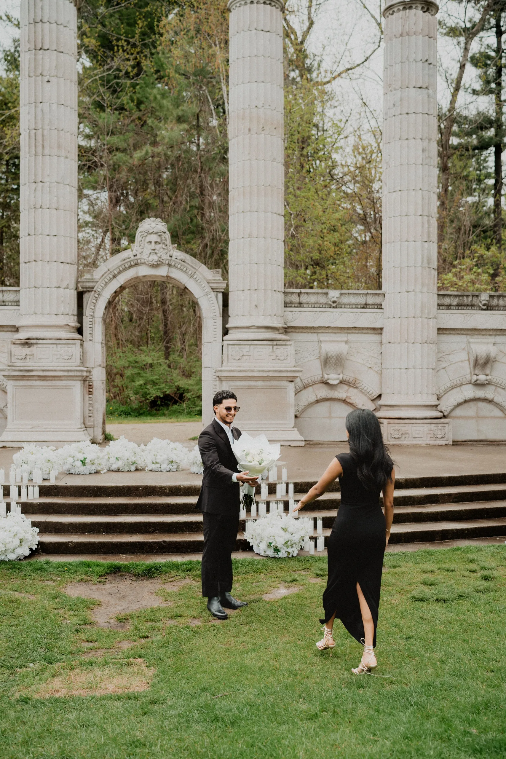 Lavina crossing the lawn toward Raeed as he holds out the bouquet at Guild Park and Gardens, by AD Photography