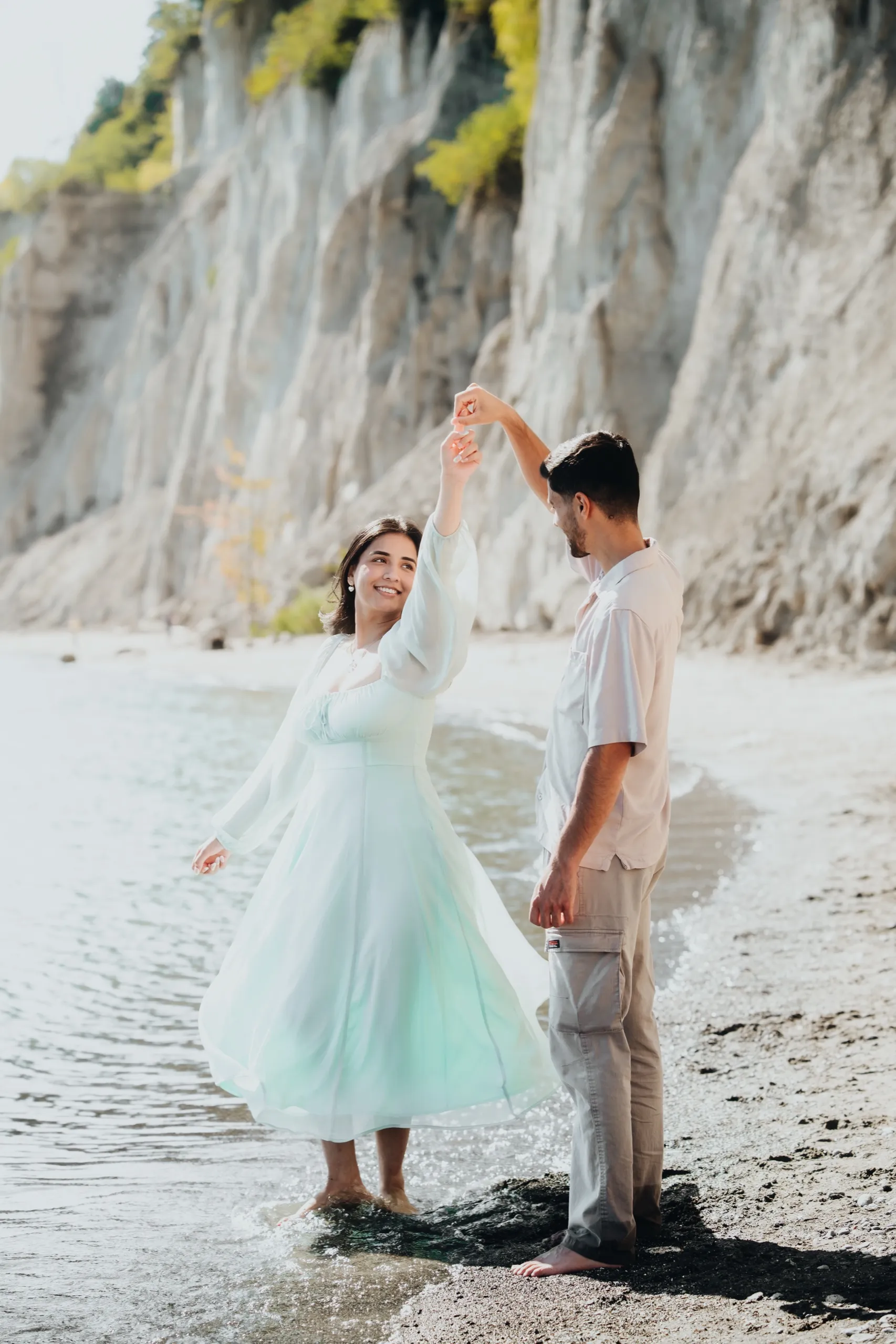 Swati twirls under Saksham's arm at the waterline during their Toronto pre-wedding shoot, by AD Photography