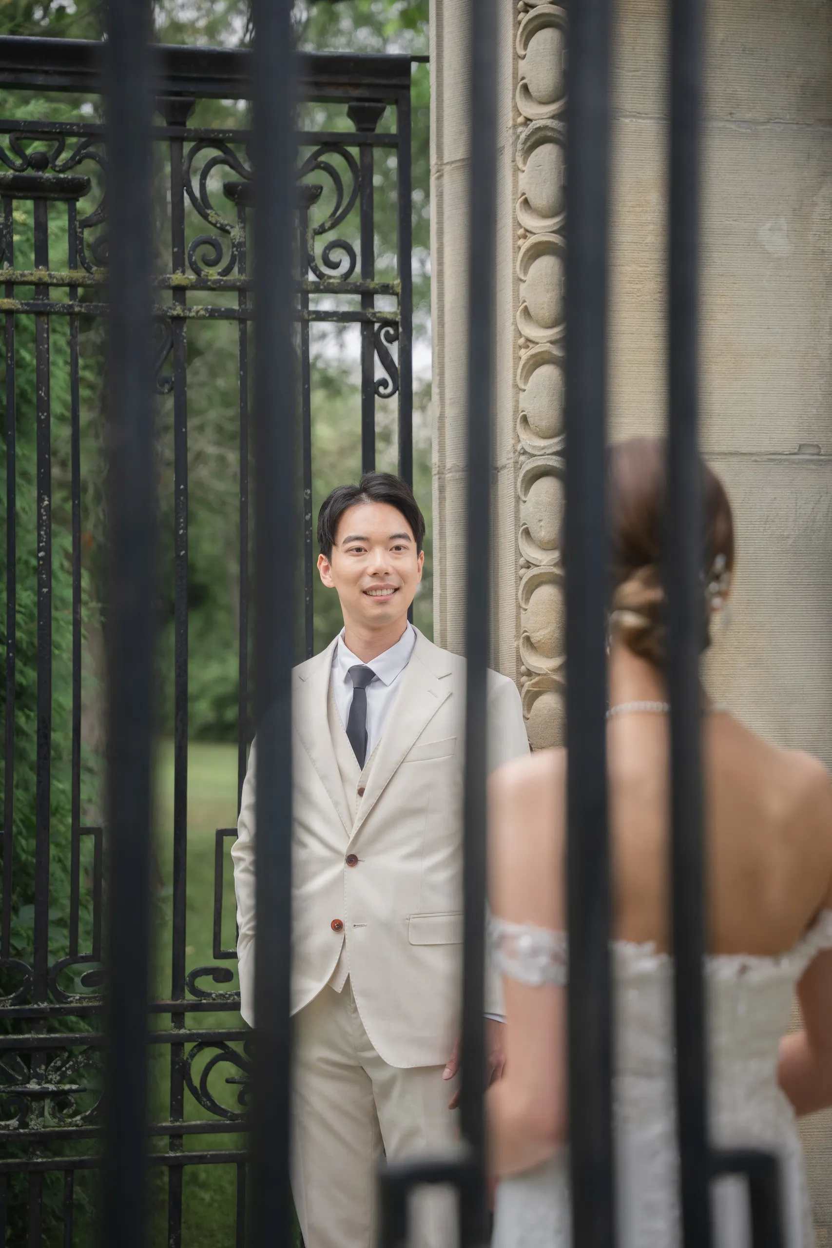 Shot through the iron gate bars, Nelson smiling at Josie before their wedding, by AD Photography
