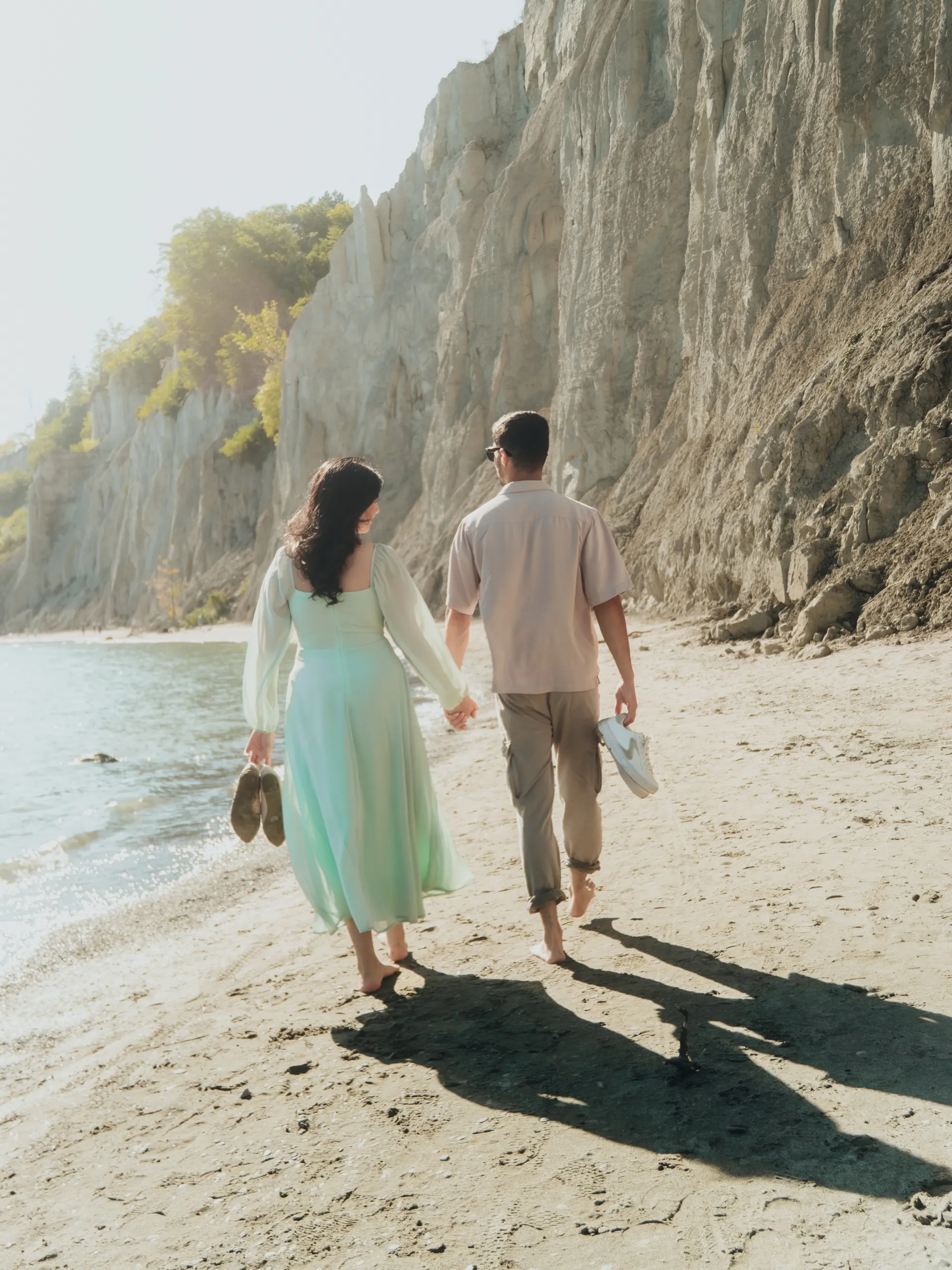 Barefoot walk along Bluffs Beach, shoes in hand, as the couple heads up the shore, by AD Photography