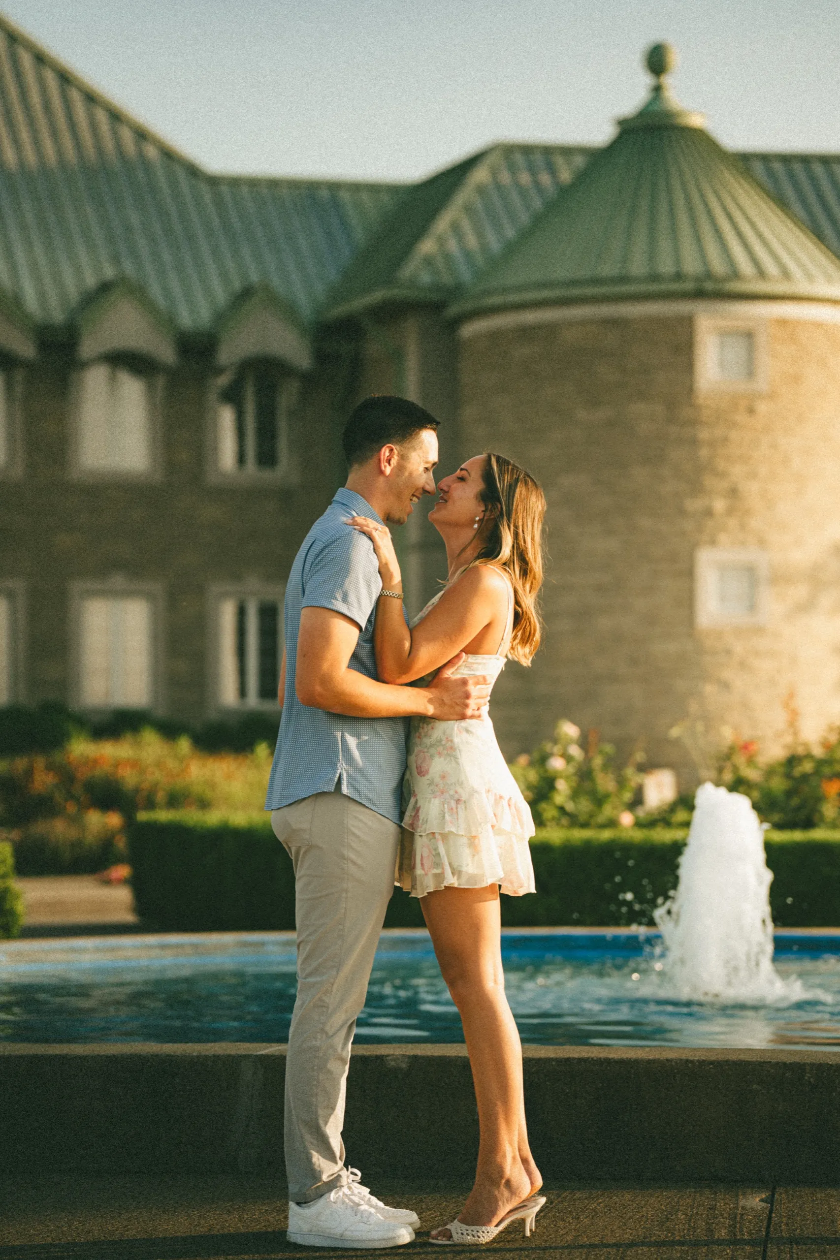 Ashley and Donald nose to nose beside the fountain, the green château roof behind them, by AD Photography