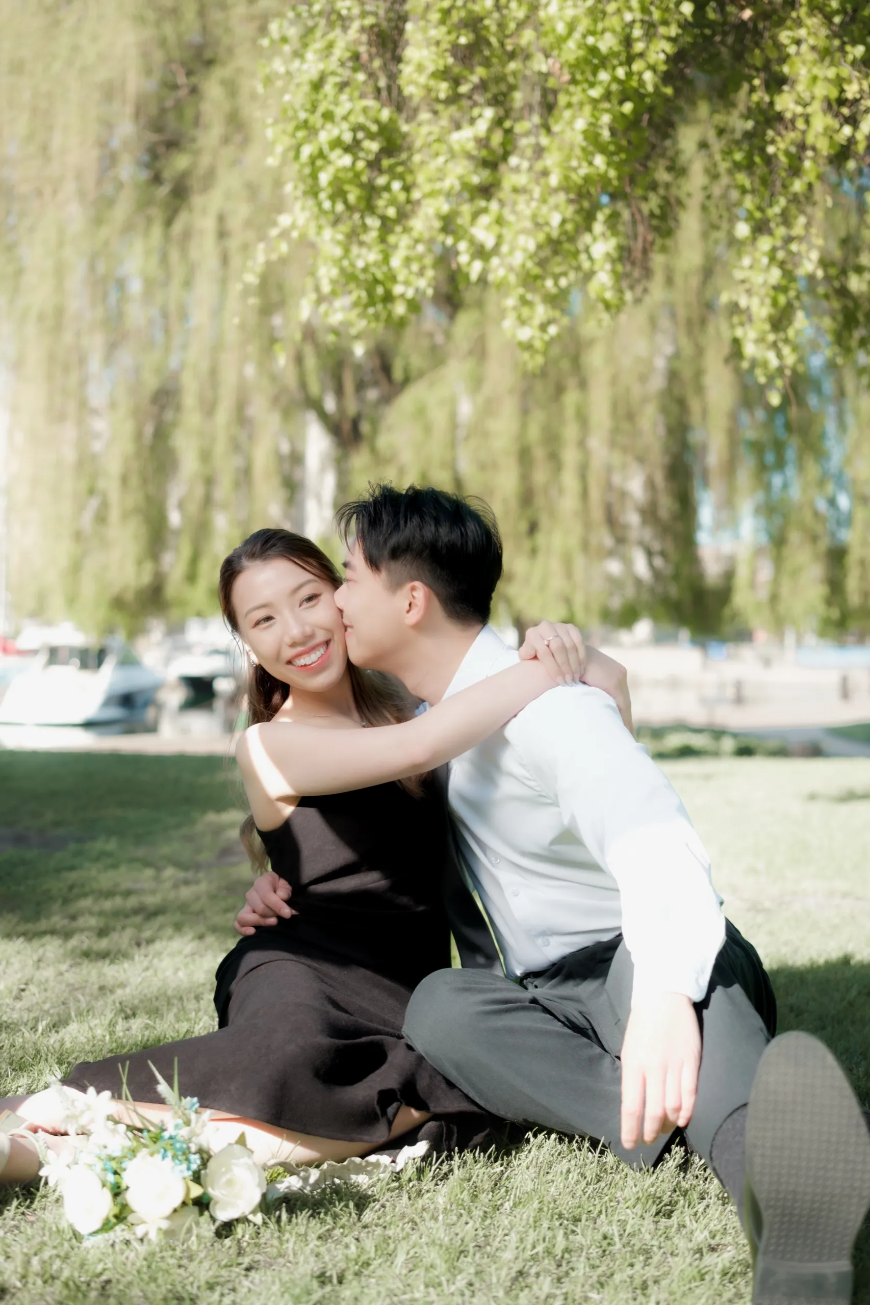 Nelson kisses Josie on the cheek beneath the draping branches of the weeping willow at the Toronto Music Garden, by AD Photography