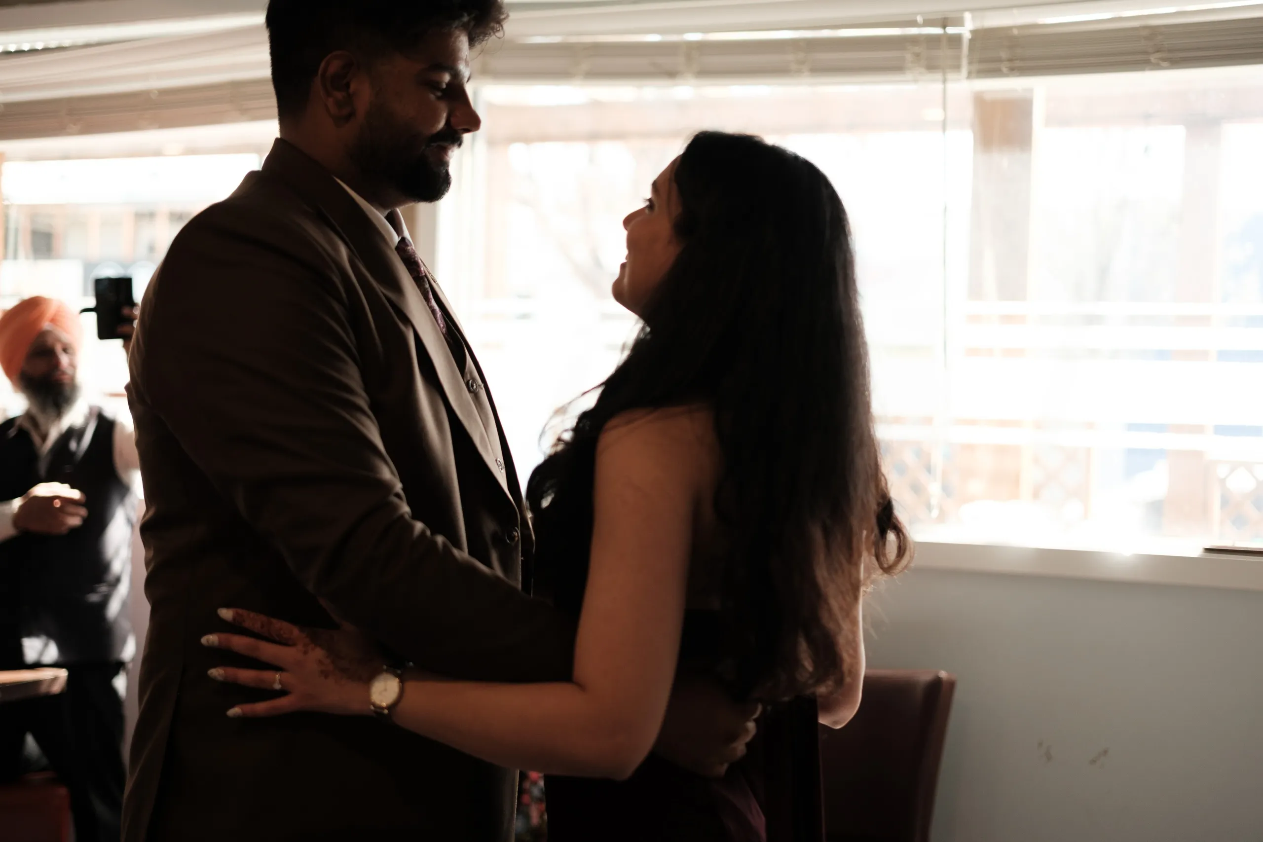 The couple holding each other by a bright window during their civil ceremony reception, by AD Photography