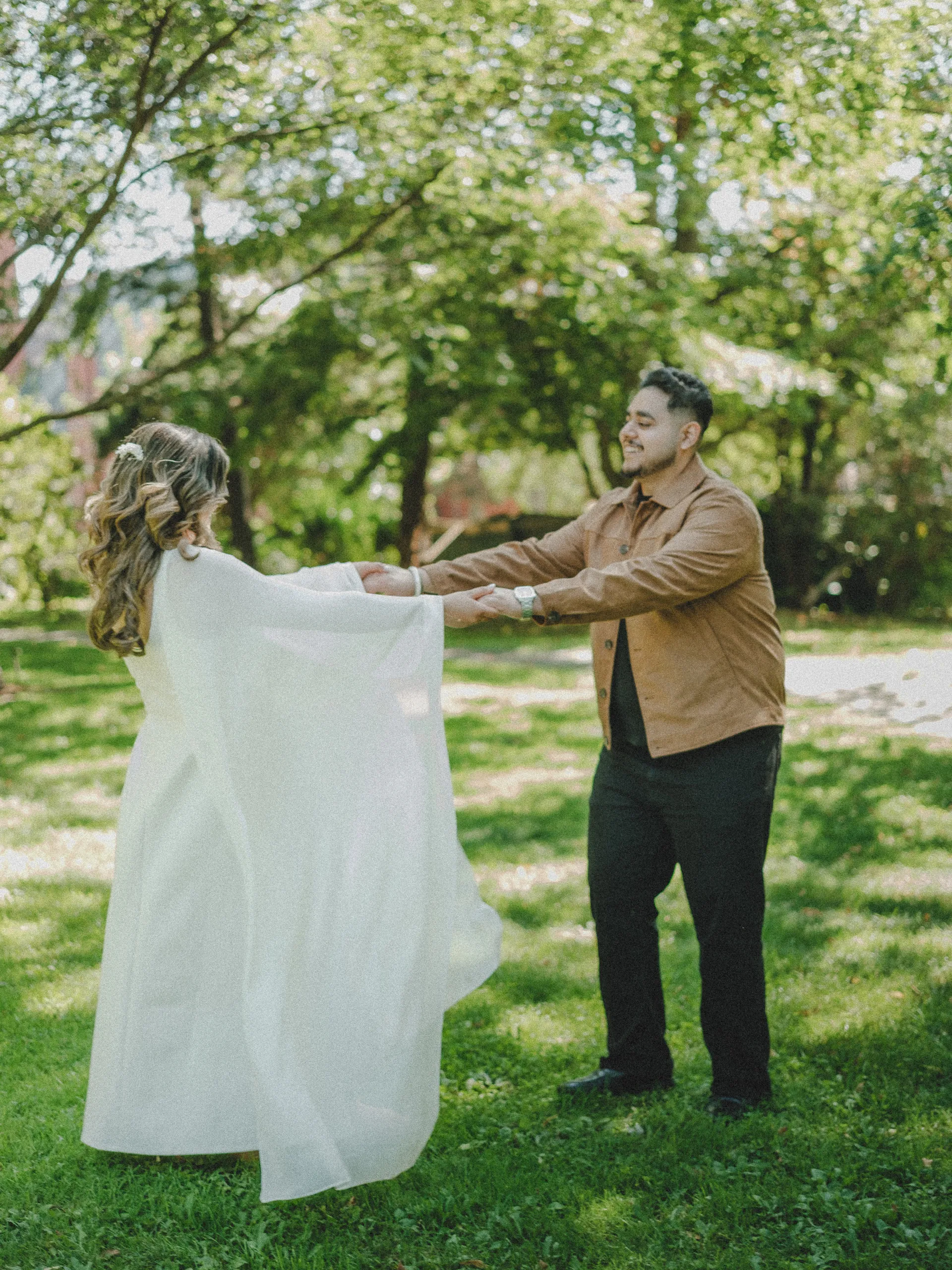 Parneet spins with both hands in Maninder's, her cape opening like wings under the big old trees, by AD Photography