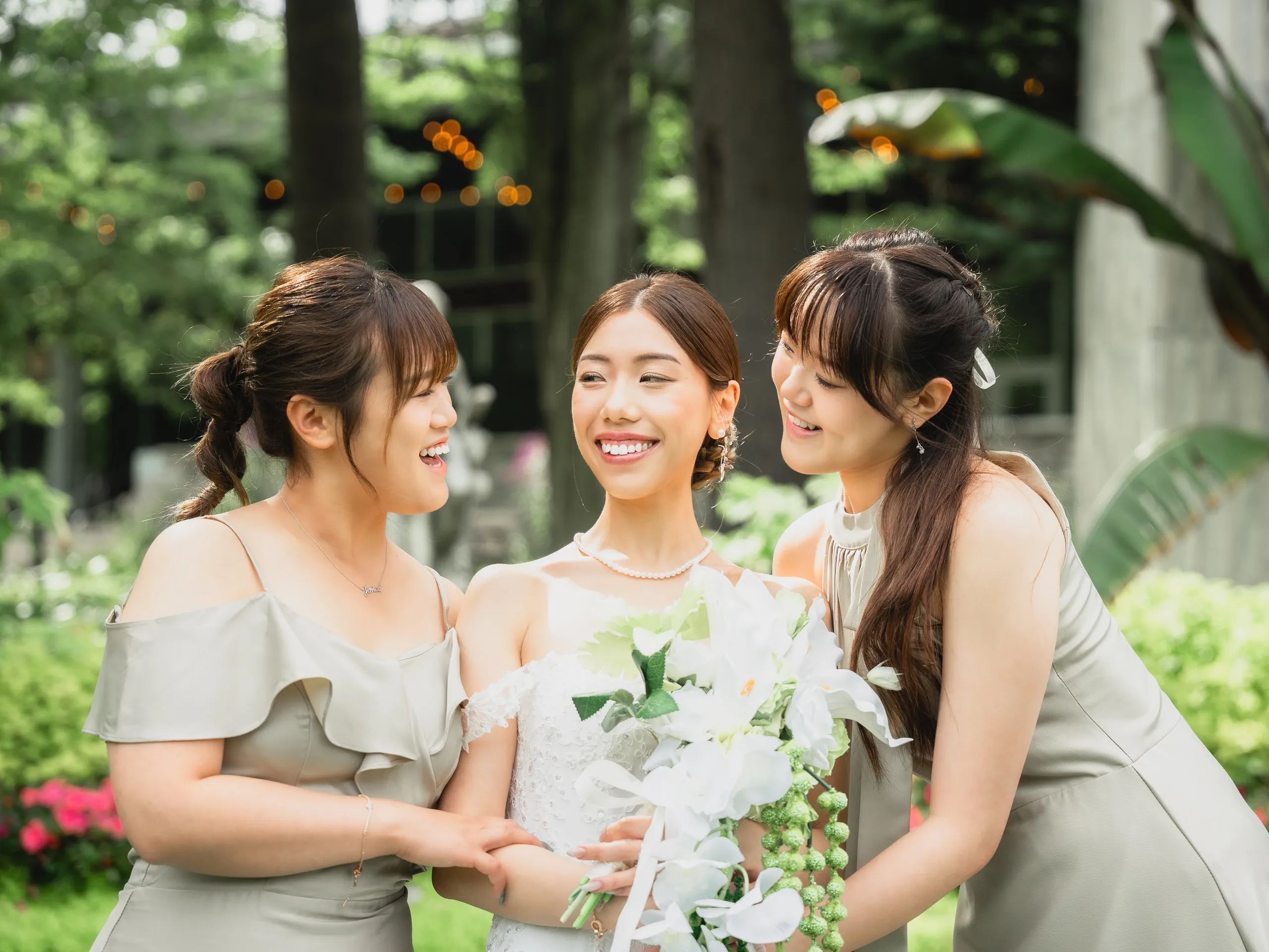 Josie laughing with her bridesmaids in sage green as they hold her wedding bouquet, by AD Photography