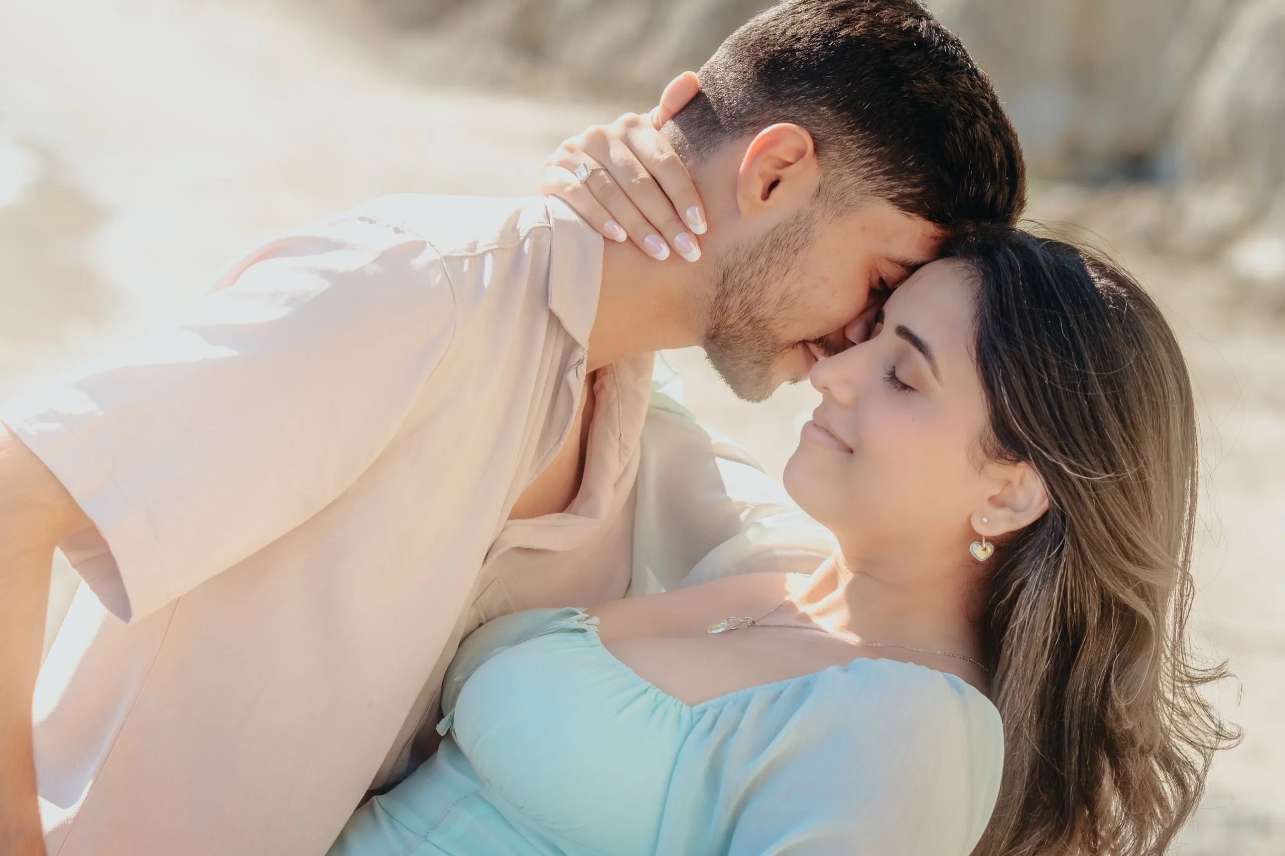 Noses almost touching in a soft close up as Saksham dips Swati on the sand, by AD Photography
