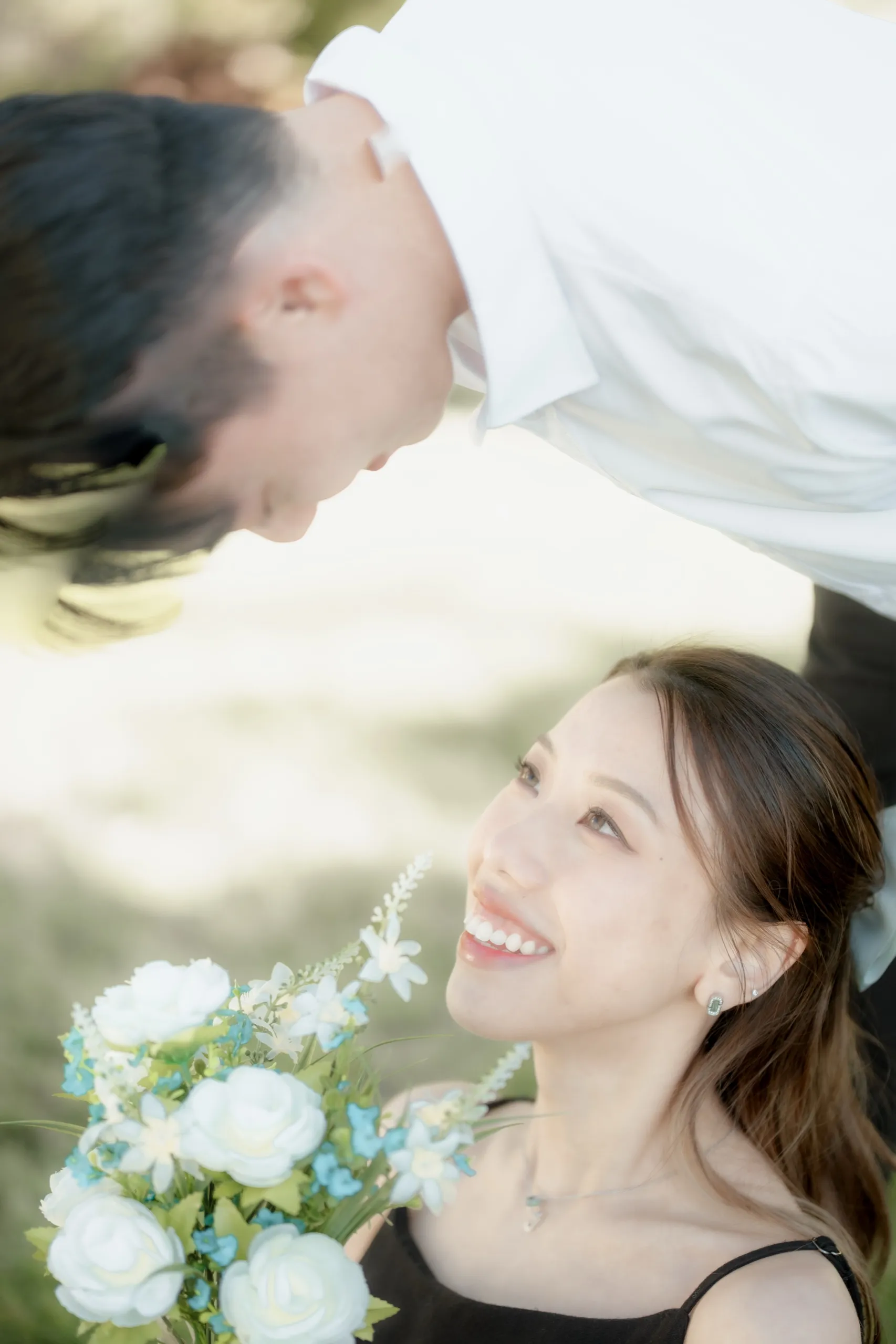 Overhead frame of Josie looking up and laughing with her bouquet as Nelson leans close, by AD Photography