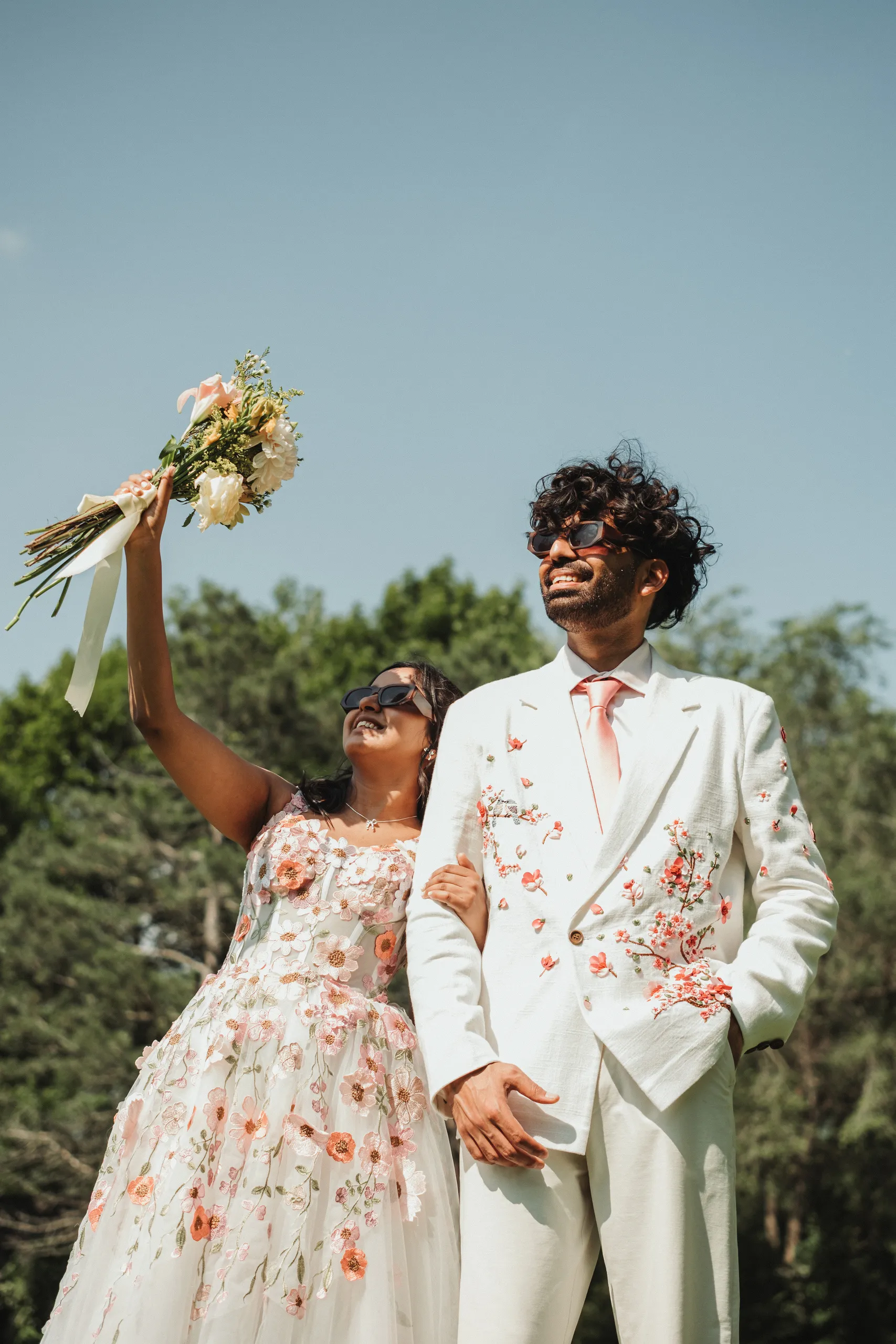 Payal raising her bouquet to the sky beside Harsh on the Toronto Islands, by AD Photography