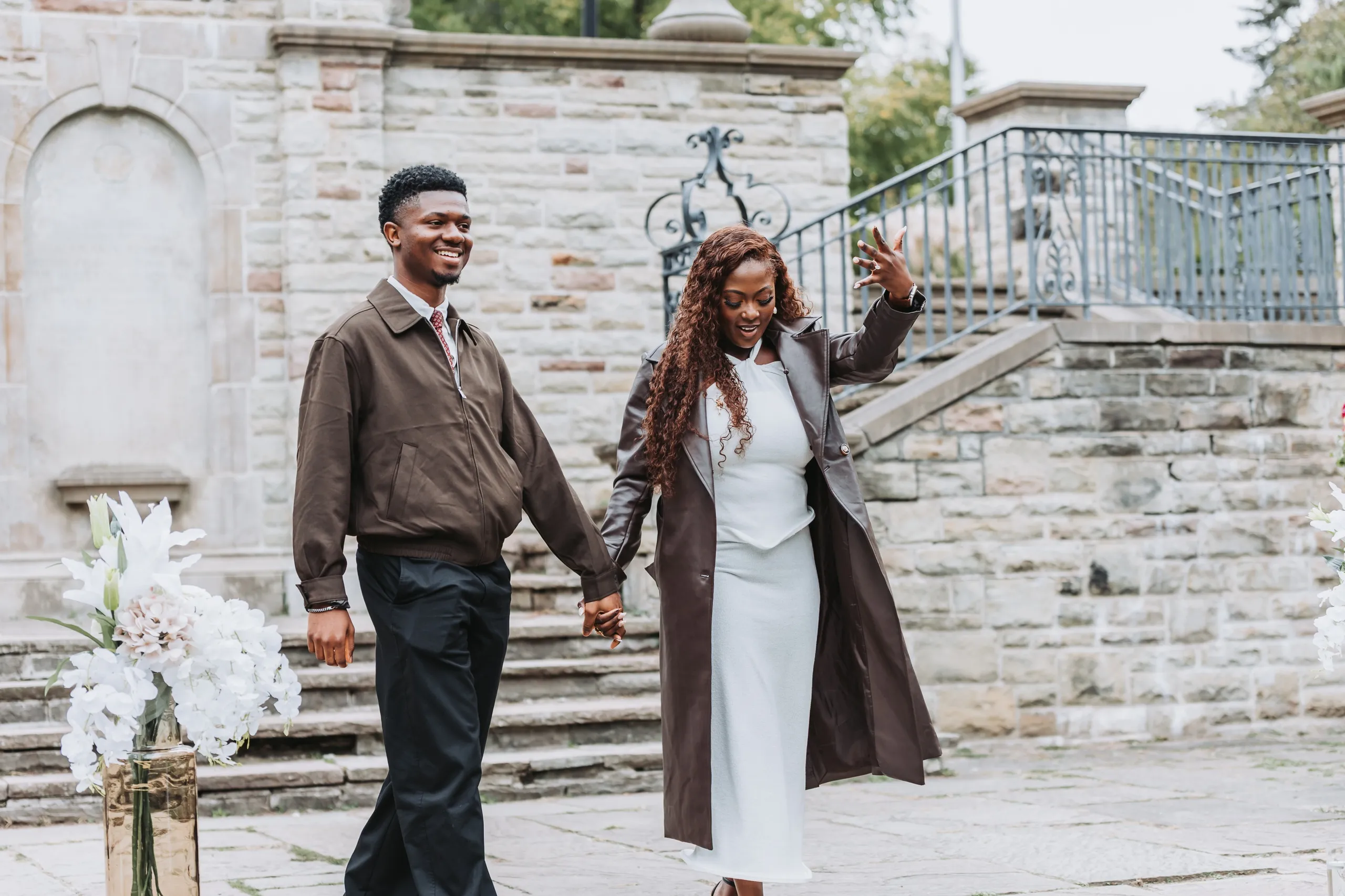 Aimee waving a hand in the air as they walk off the terrace laughing, by AD Photography