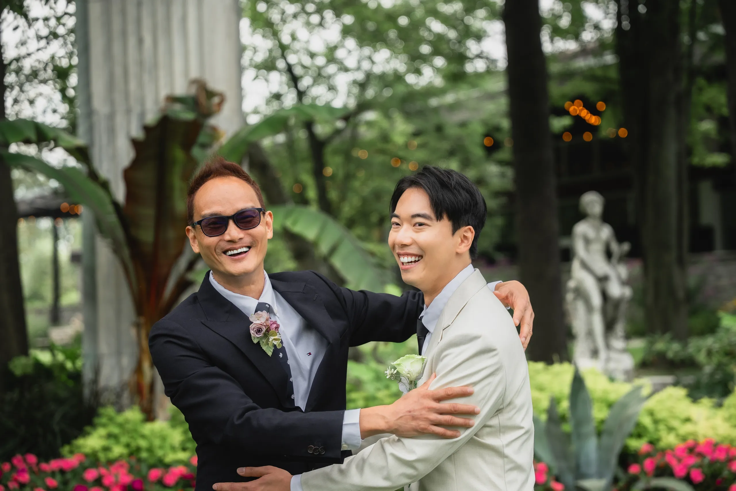 Nelson laughing as a suited guest in sunglasses pulls him into a hug, by AD Photography