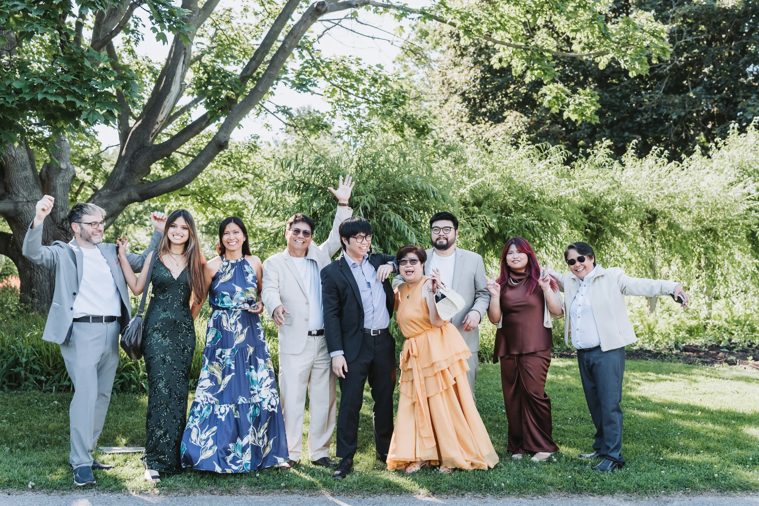 Wedding guests cheering with their arms raised on the lawn at the Niagara Parks Botanical Gardens, by AD Photography