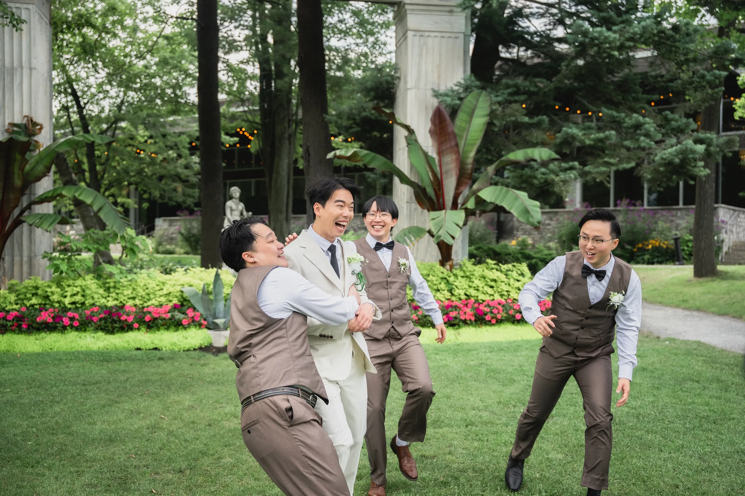 Nelson's groomsmen piling into a laughing group hug on the Guild Park lawn, by AD Photography