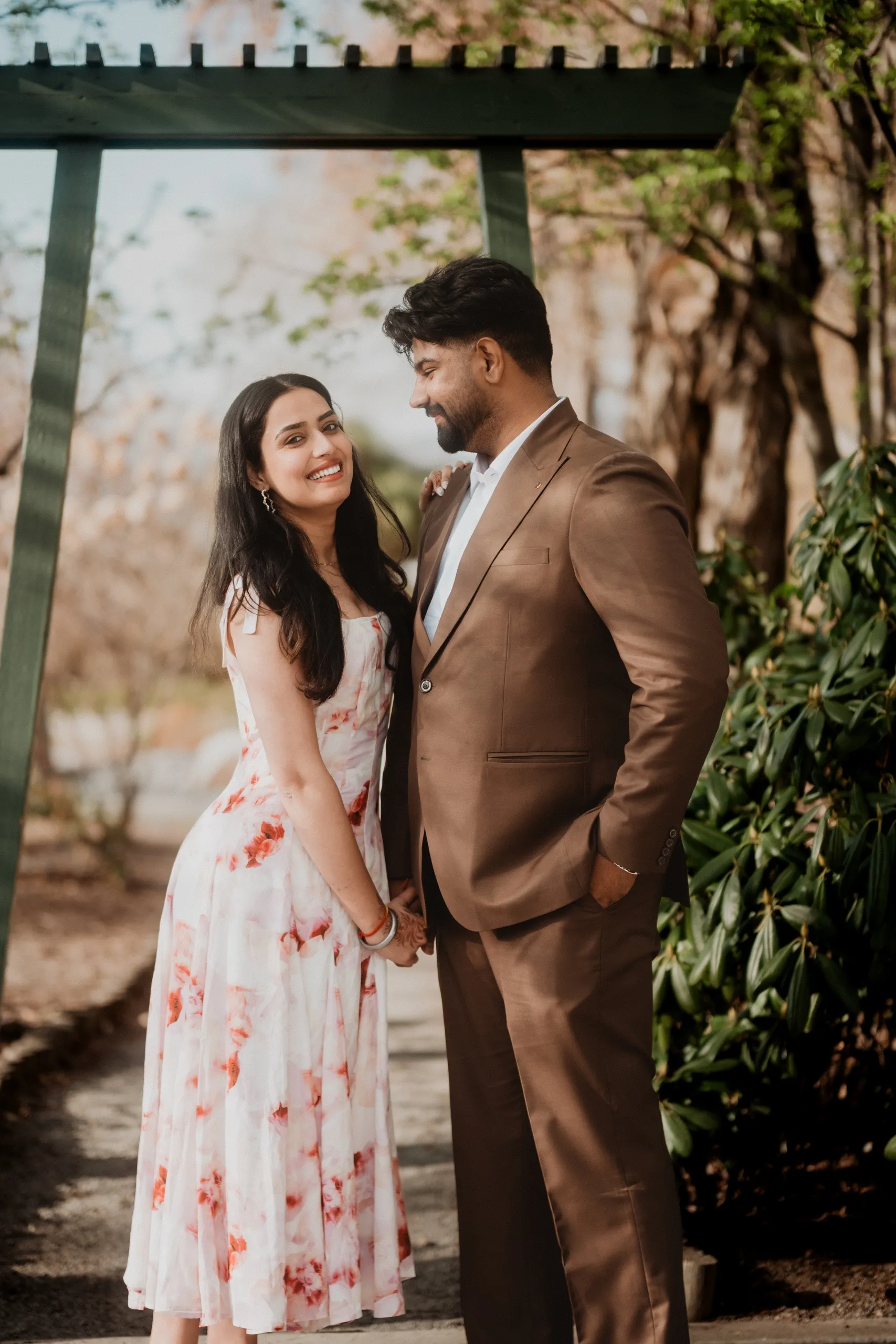 Mehak laughing up at Kamal beneath a green torii gate in the Japanese garden, by AD Photography