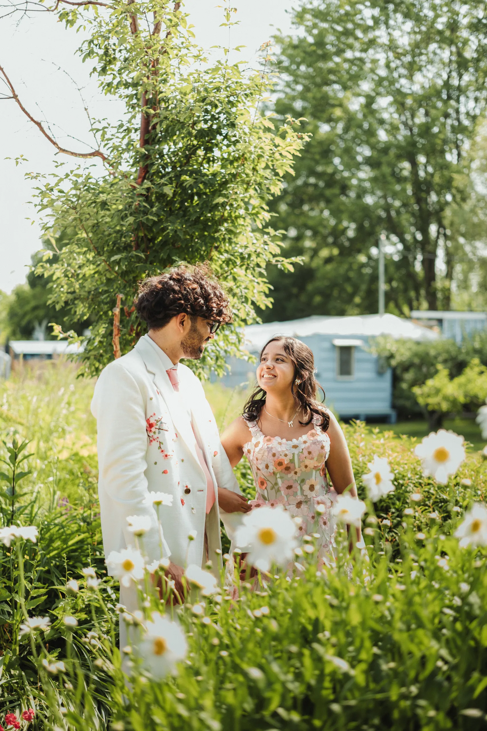 Harsh and Payal in a close tender moment framed by white daisies on the Toronto Islands, by AD Photography