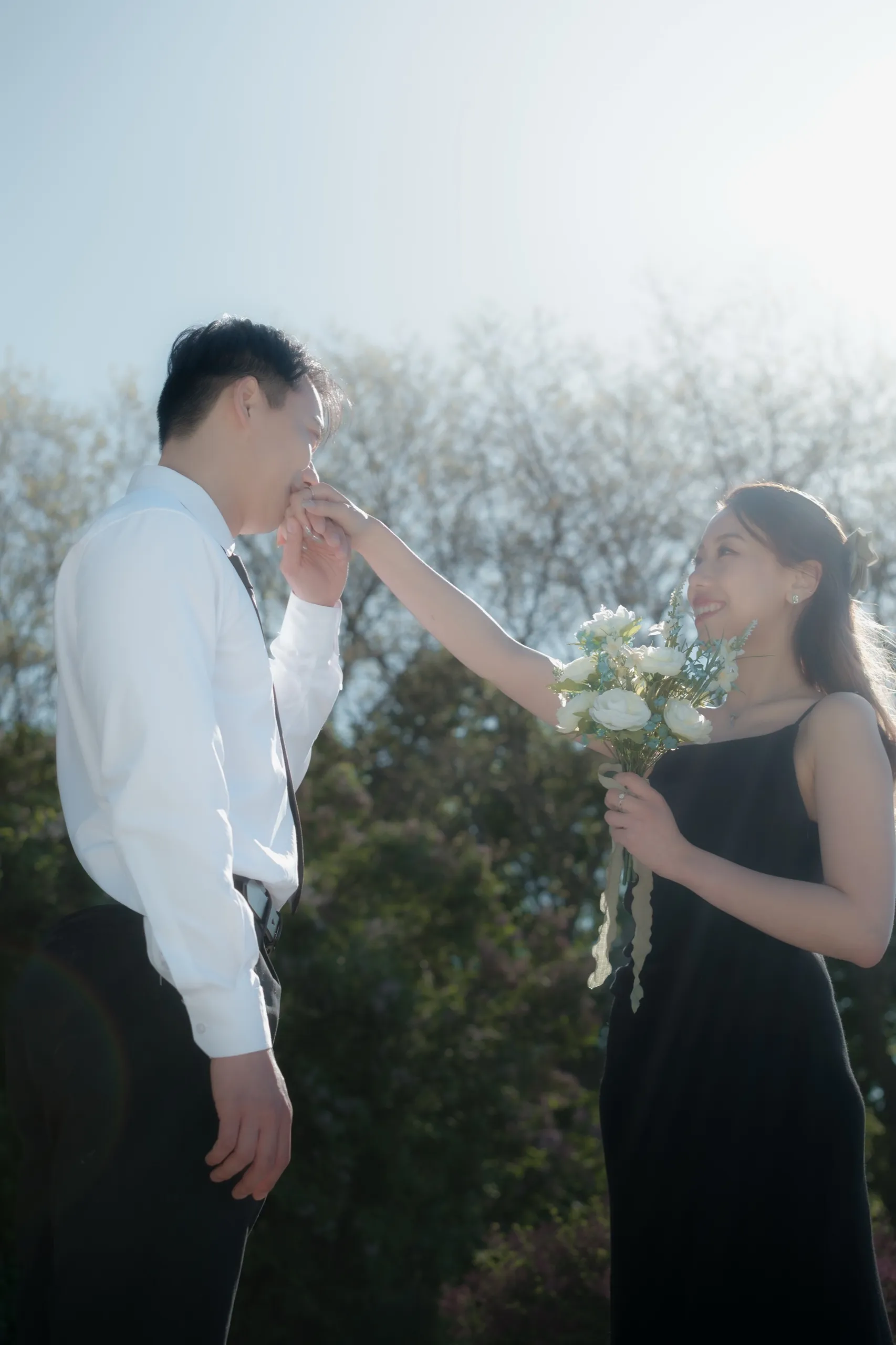 Backlit hazy moment as Nelson kisses Josie's hand in the warm afternoon light, by AD Photography