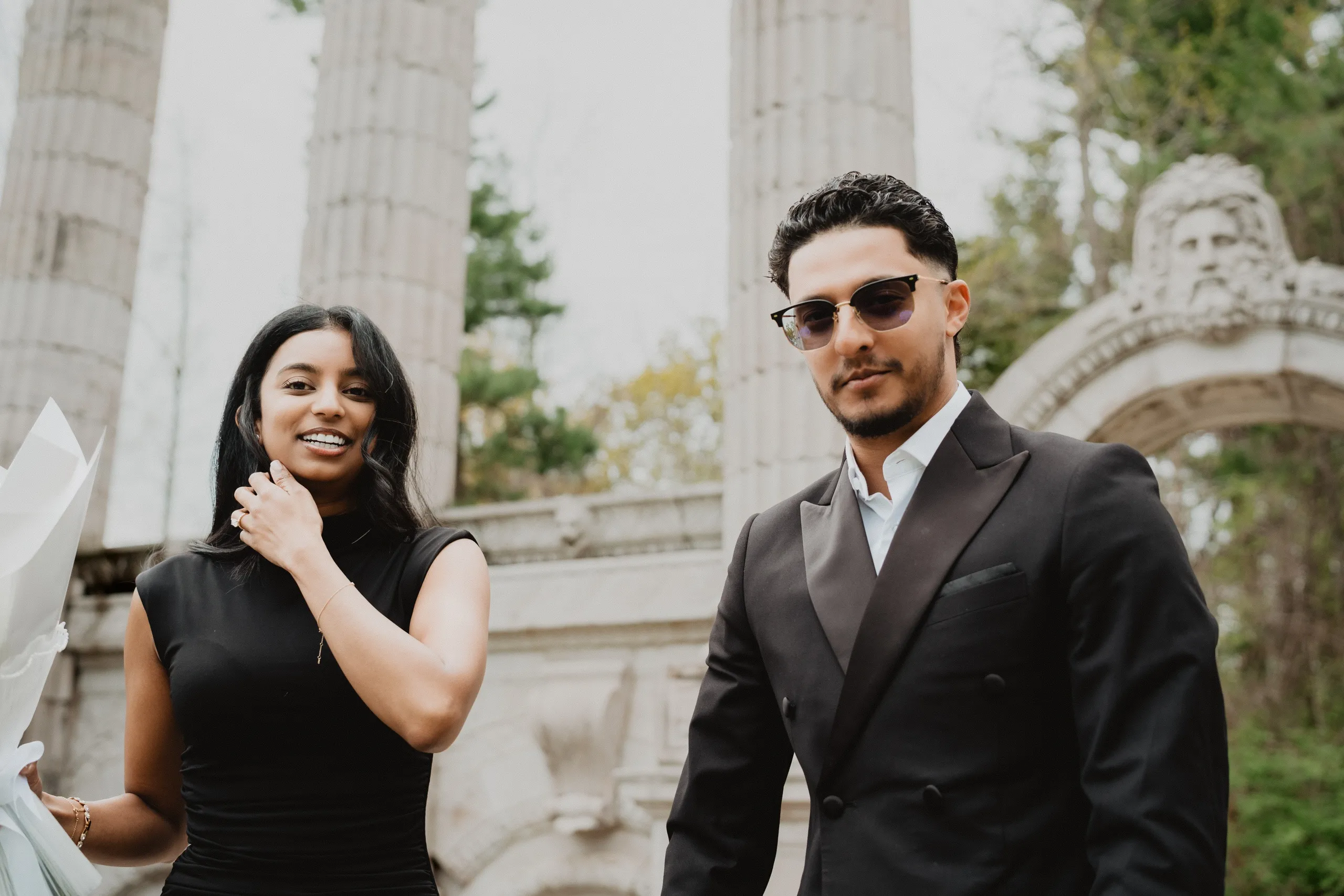 Lavina and Raeed looking straight to camera at Guild Park and Gardens, her ring at her collar, by AD Photography