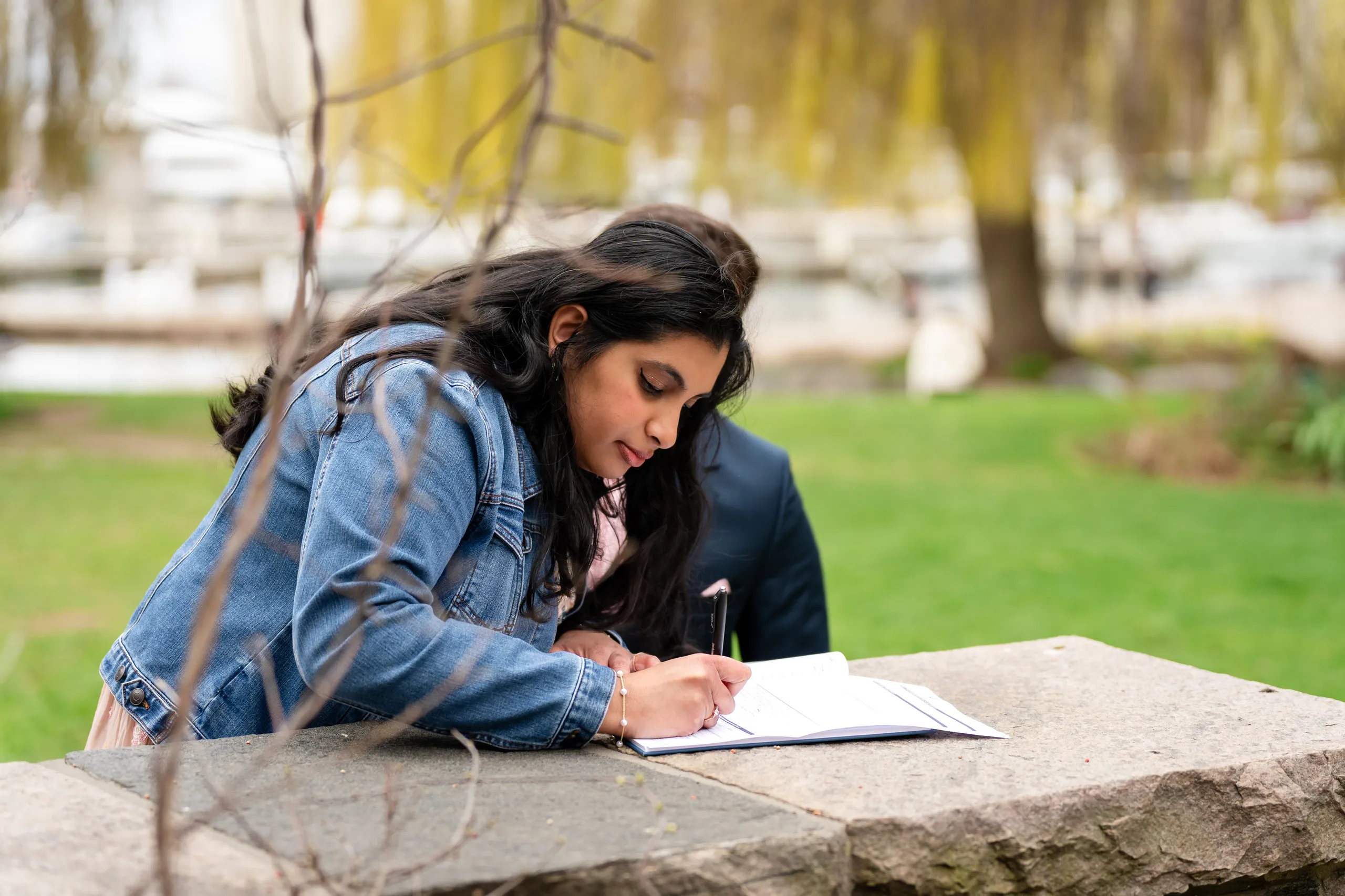 Nadia signs the marriage register through a veil of spring branches at Toronto Music Garden, by AD Photography