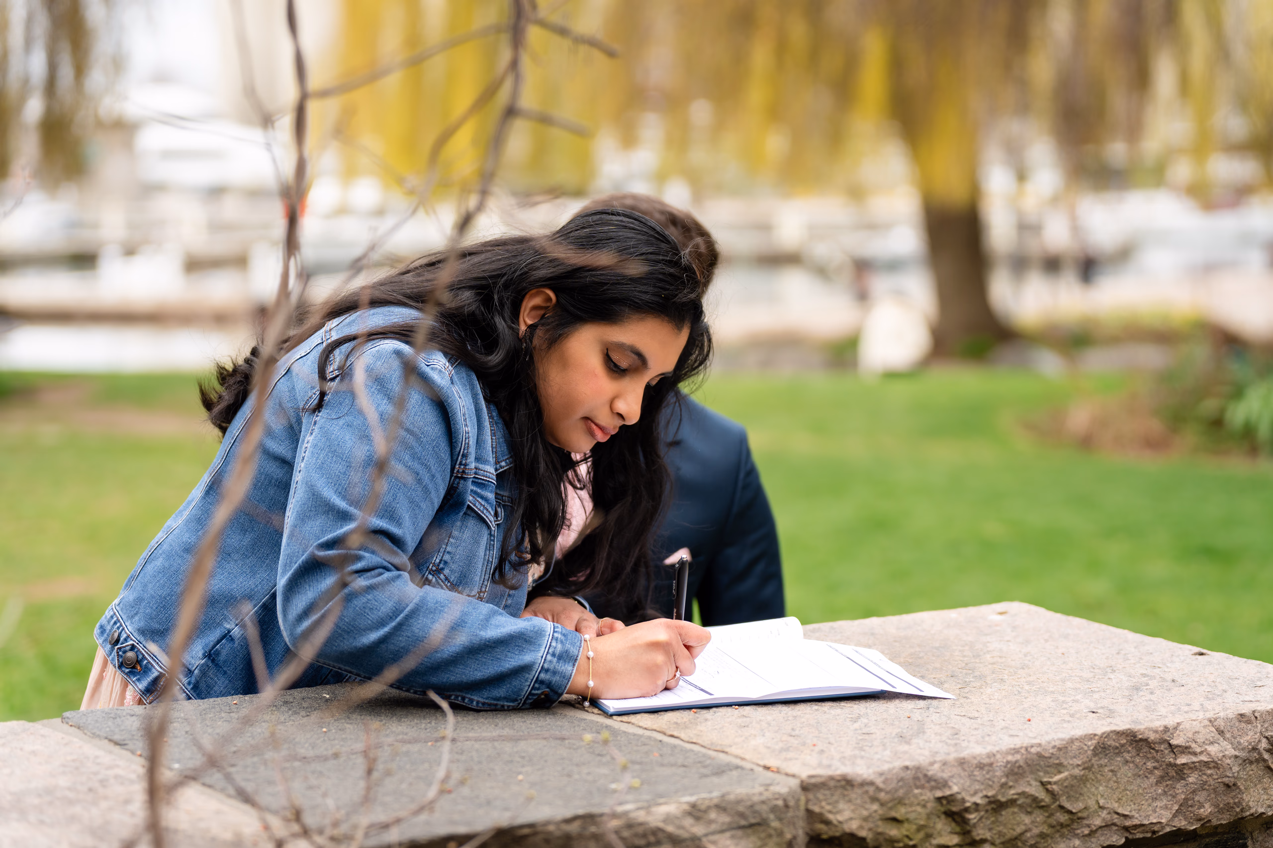 Nadia signs the marriage register through a veil of spring branches at Toronto Music Garden
