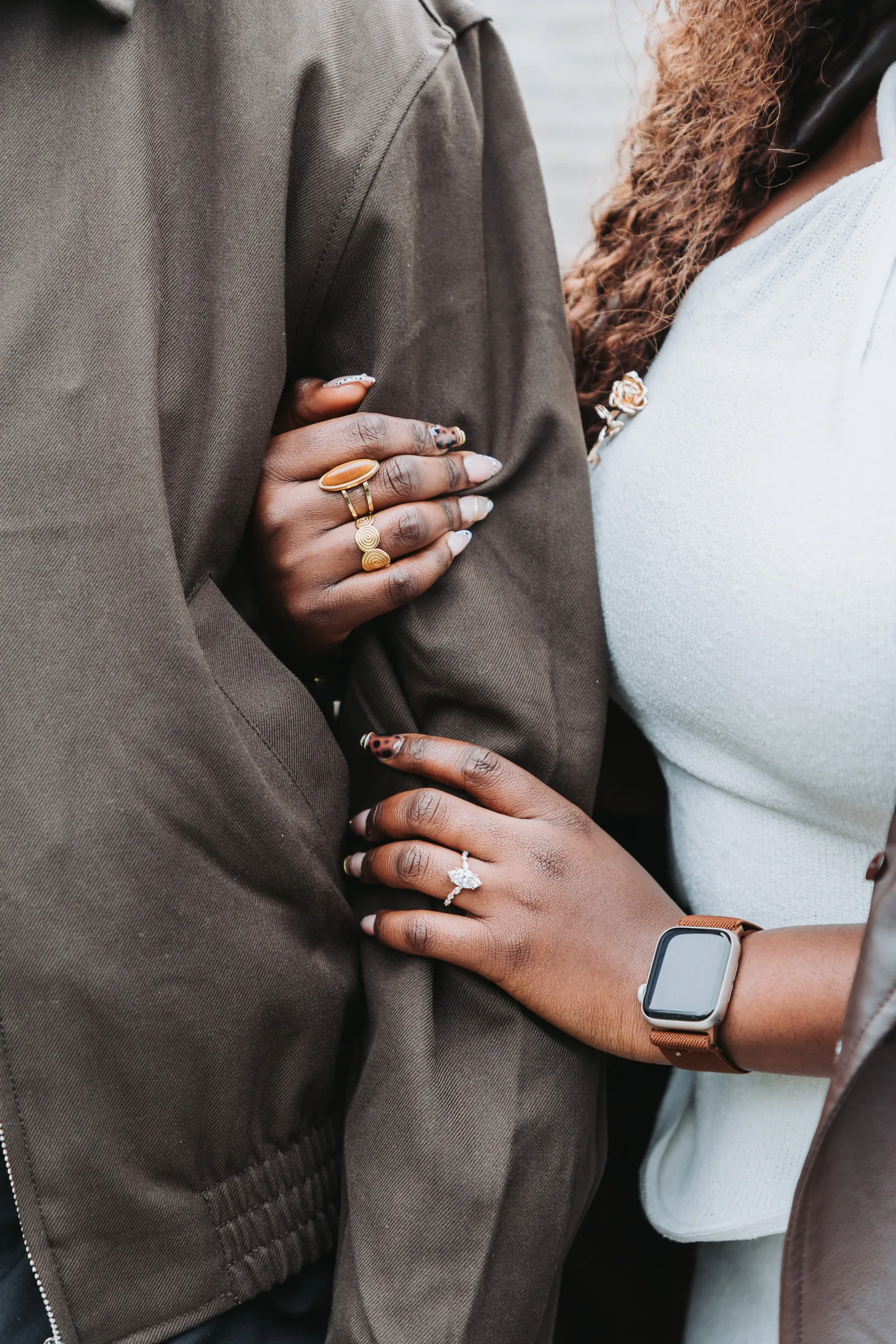 Aimee's hand with her new ring linked through Richie's arm on his brown jacket, by AD Photography