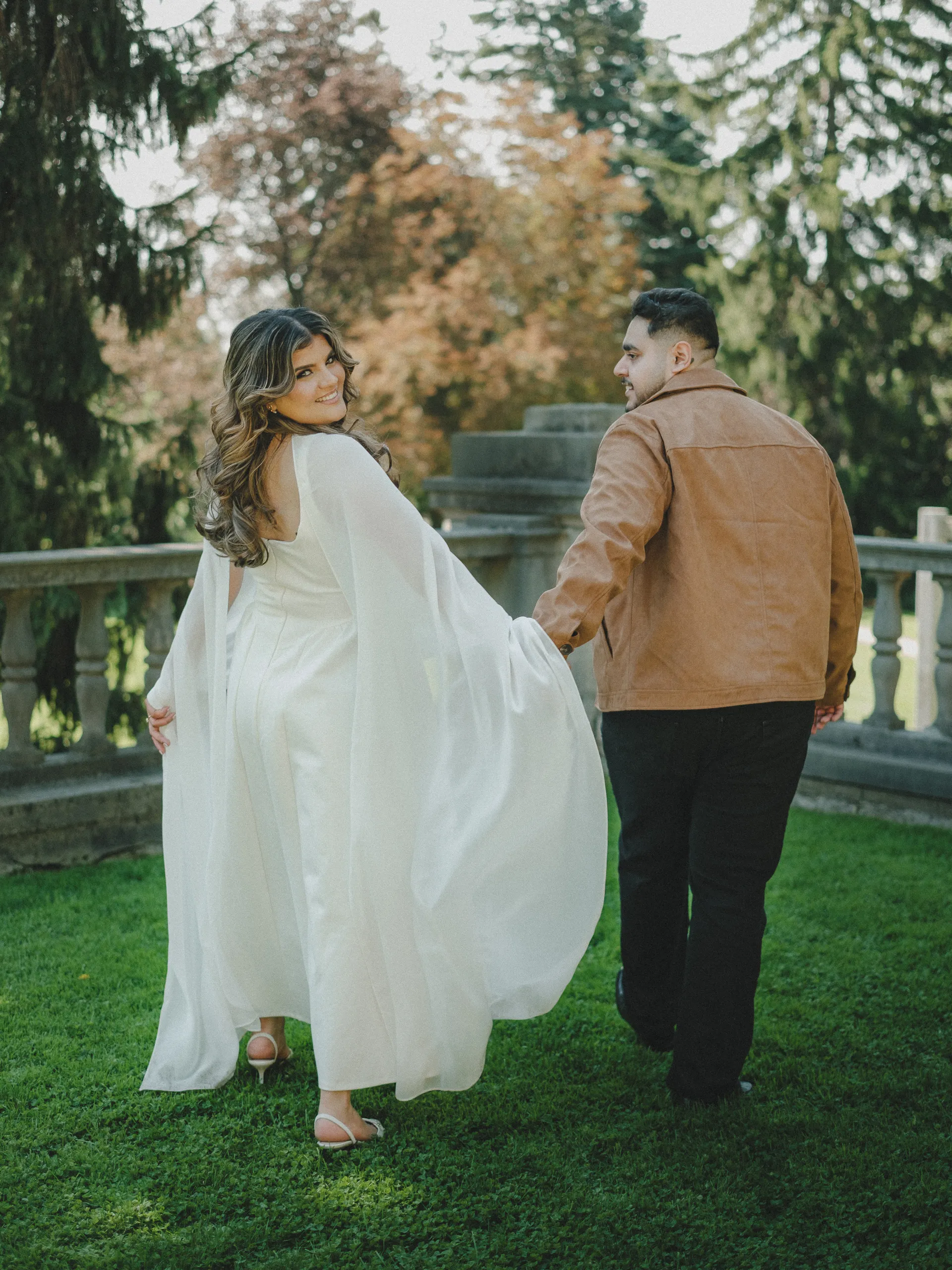 Parneet looks back over her shoulder, cape sweeping, as Maninder leads her toward the terrace balustrade, by AD Photography